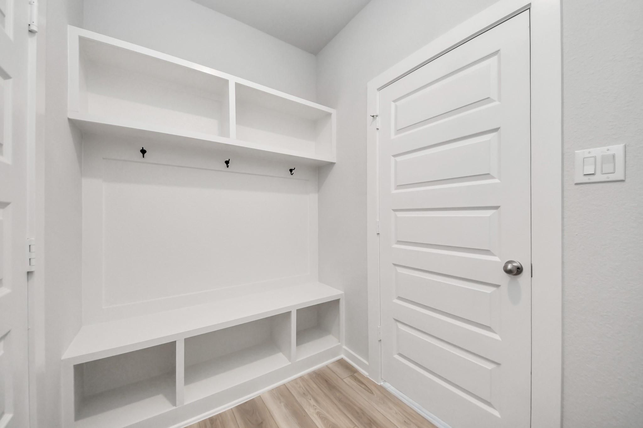 Built-in white mudroom bench with storage cubbies and coat hooks in The Sabine F floor plan, Liberty Estates, Texas.