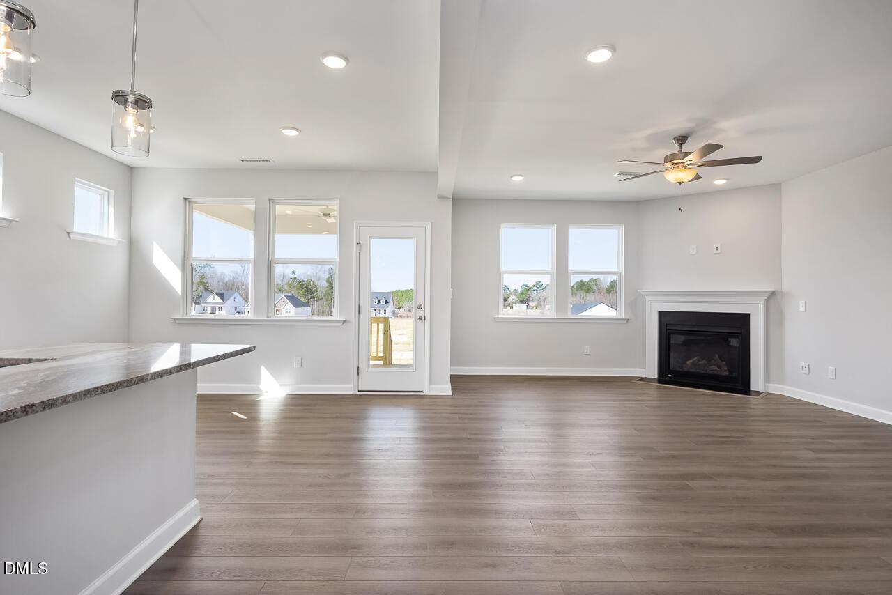 Open-concept great room featuring granite island, gas fireplace, hardwood floors, large windows, and French doors to backyard in Davidson Homes The Willow G, Angier NC