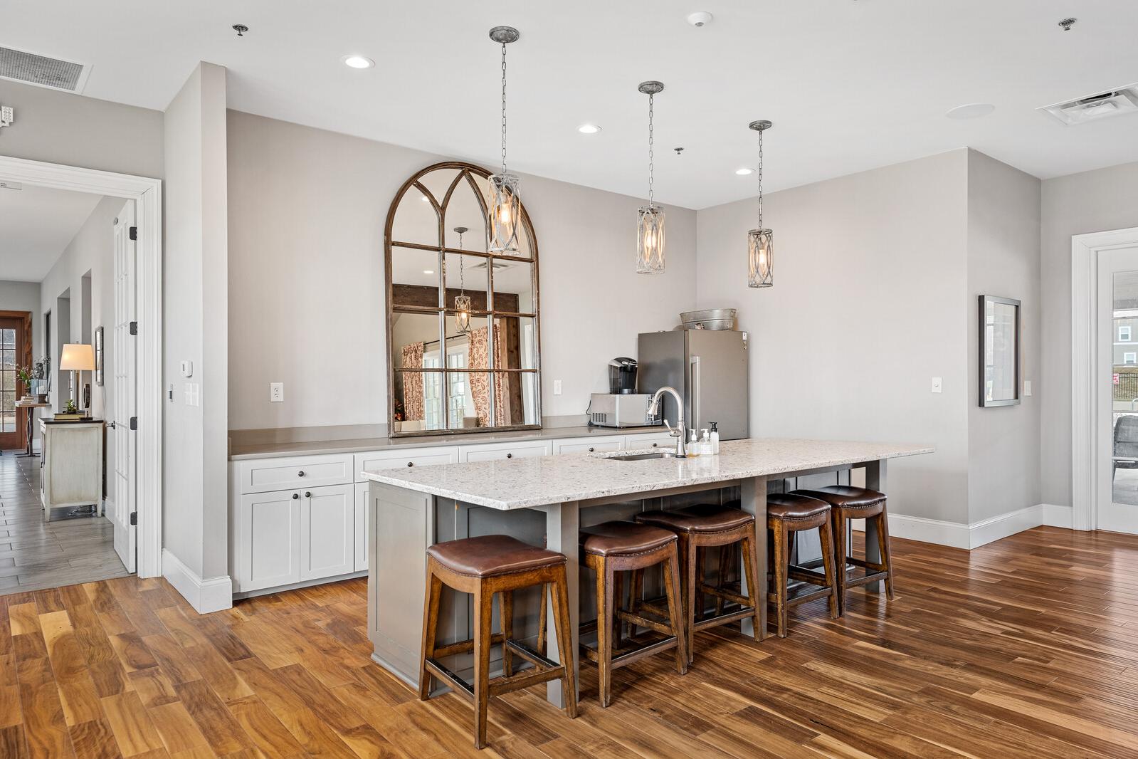 Spacious community kitchen at Carellton in Gallatin TN with quartz island, leather barstools, arched mirror, pendant lights and hardwood floors