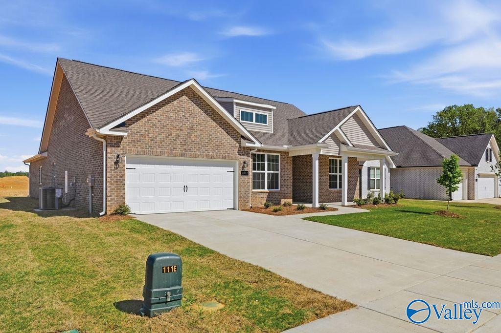 Modern brick 1-story home with 2-car garage, covered porch, and lush yard in Cain Park, Hartselle, Alabama
