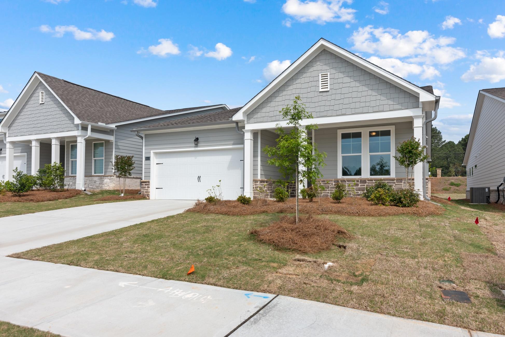 The Dawson A single-story home exterior with gray siding, two-car garage, front porch, and landscaped yard in Loganville GA