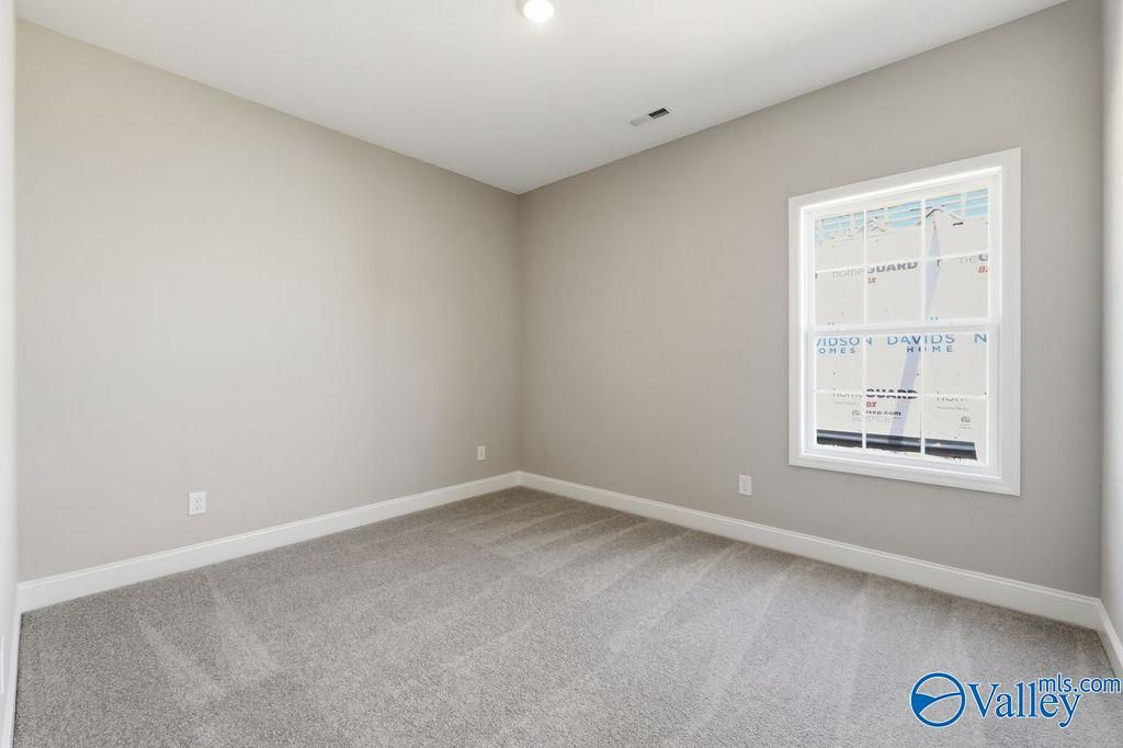 Spacious bedroom with grey carpet and neutral walls in The Rockford floor plan at Cain Park, Hartselle, Alabama.