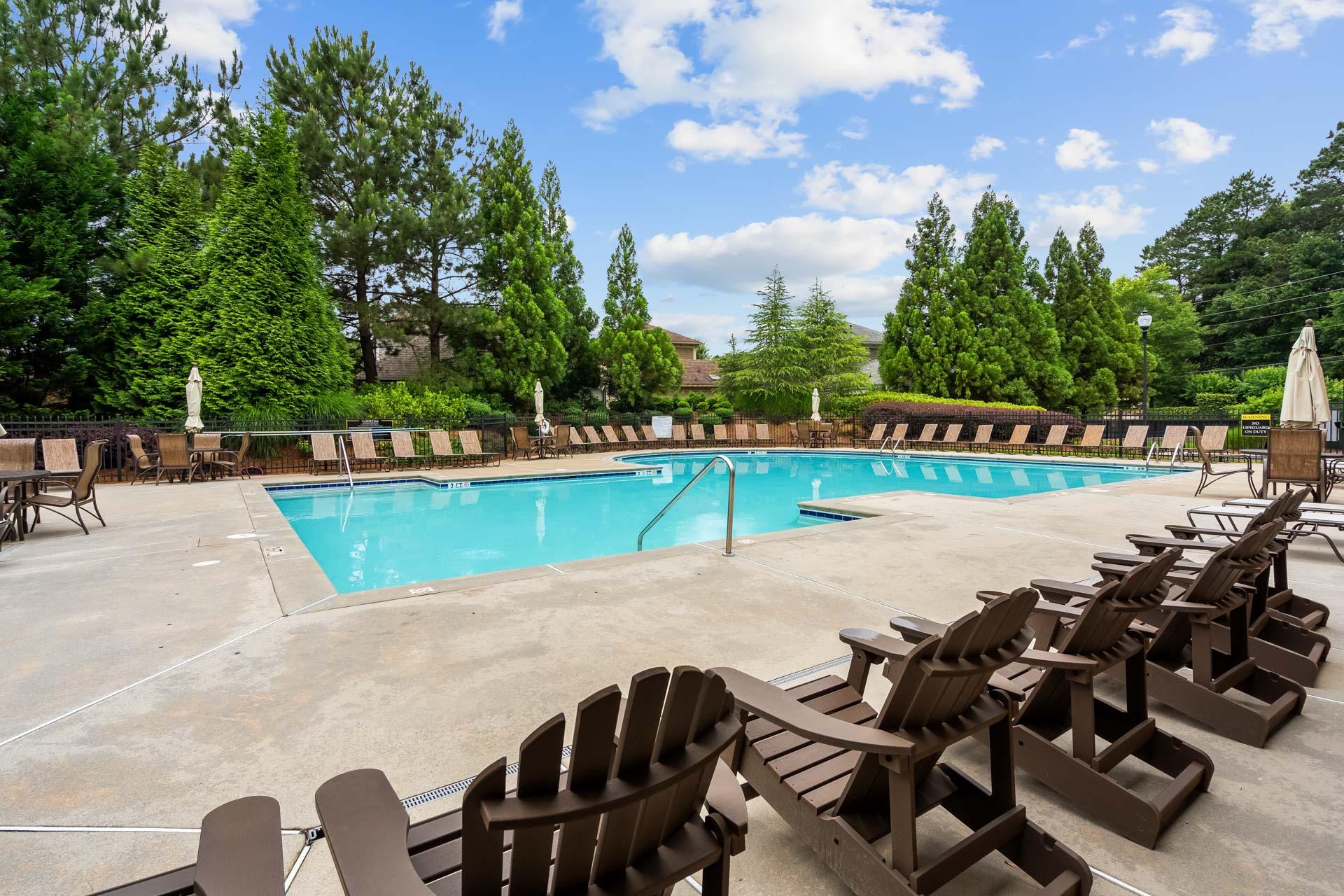 Resort-style swimming pool at The Village at Towne Lake in Woodstock Georgia with lounge chairs umbrellas and lush trees