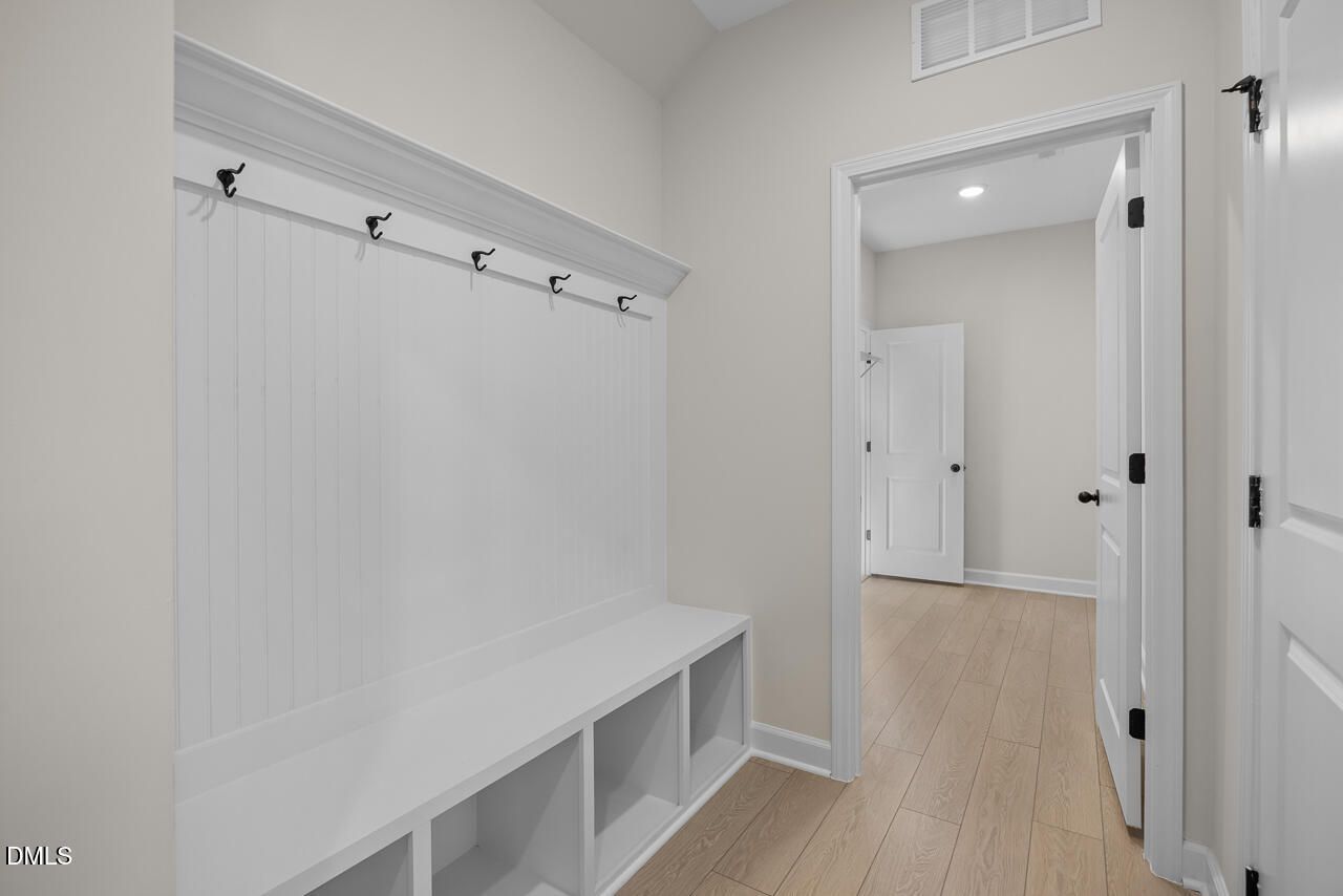 Built-in mudroom bench with beadboard wall, coat hooks, and storage cubbies in Davidson Homes The Ashport M, Wendell NC