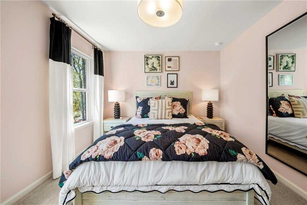 Charming girls' bedroom with floral pink duvet, bedside lamps, and window curtains in Davidson Homes The Hickory B, Riverwood, Dallas, Georgia