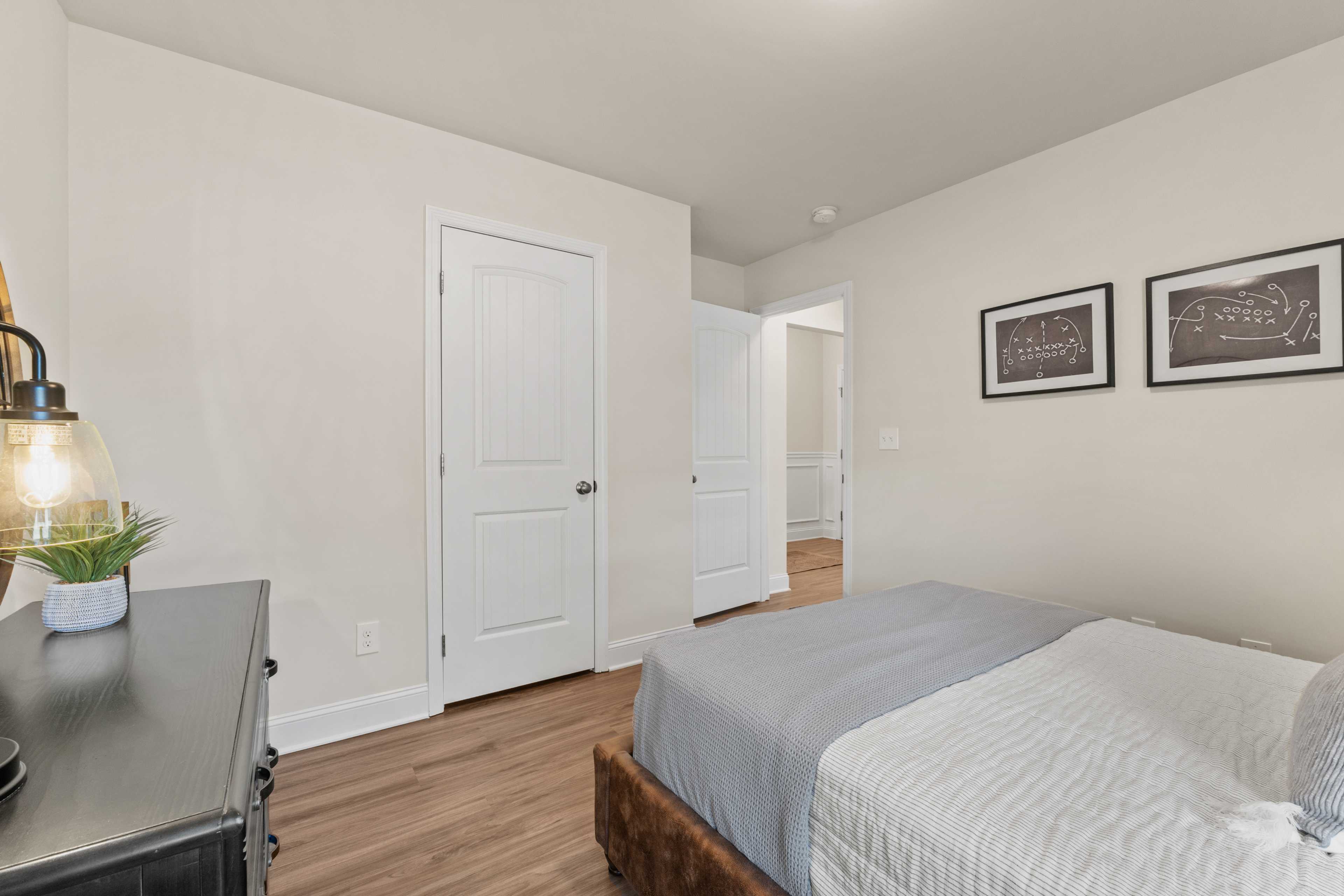 Cozy bedroom interior at Noble Ridge in Cullman AL with queen bed, hardwood floors, neutral walls, and modern dresser