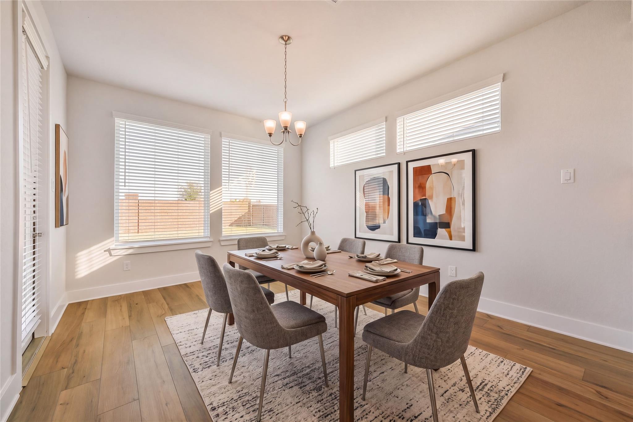 Elegant dining room featuring wooden table, gray upholstered chairs, chandelier, and abstract wall art in Davidson Homes The Victoria A, Lago Mar