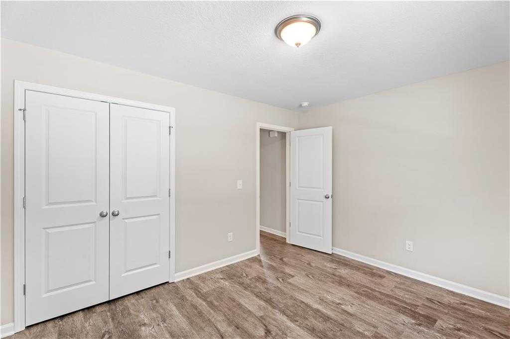 Bright bedroom with double white closet doors, adjacent bath entry, and hardwood floors in Davidson Homes The Washington, Phenix City