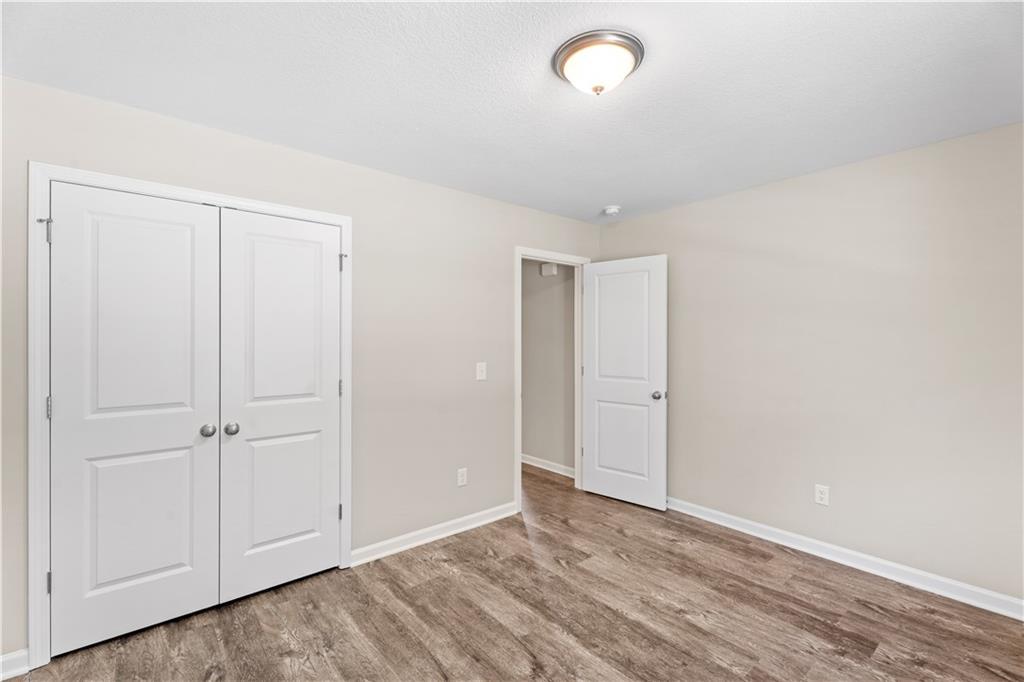 Bright bedroom with double white closet doors, adjacent bath entry, and hardwood floors in Davidson Homes The Washington, Phenix City