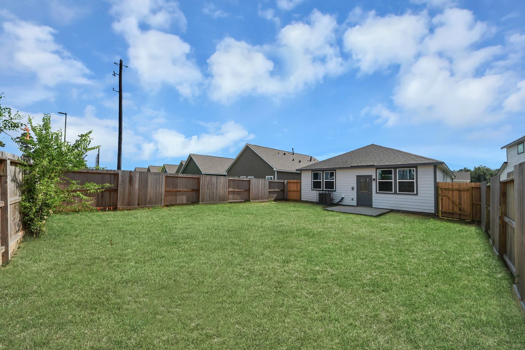 Spacious fenced backyard with green lawn at Davidson Homes The Frio F single-story home in Robins Landing, Houston, Texas