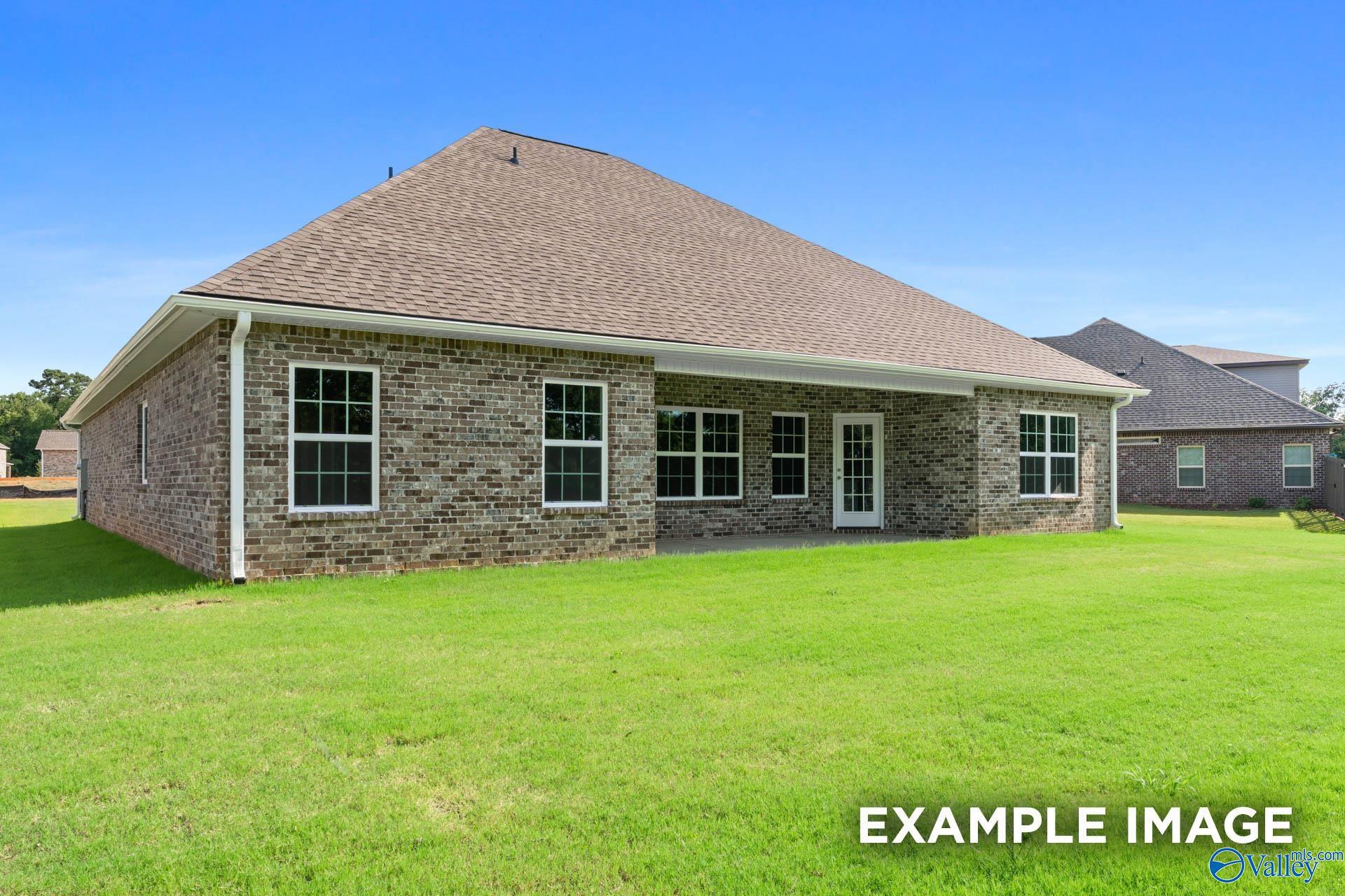 Rear brick exterior of 1.5-story Davidson Homes The Rockford with covered patio, lush green backyard in Barnett's Crossing, Madison, AL