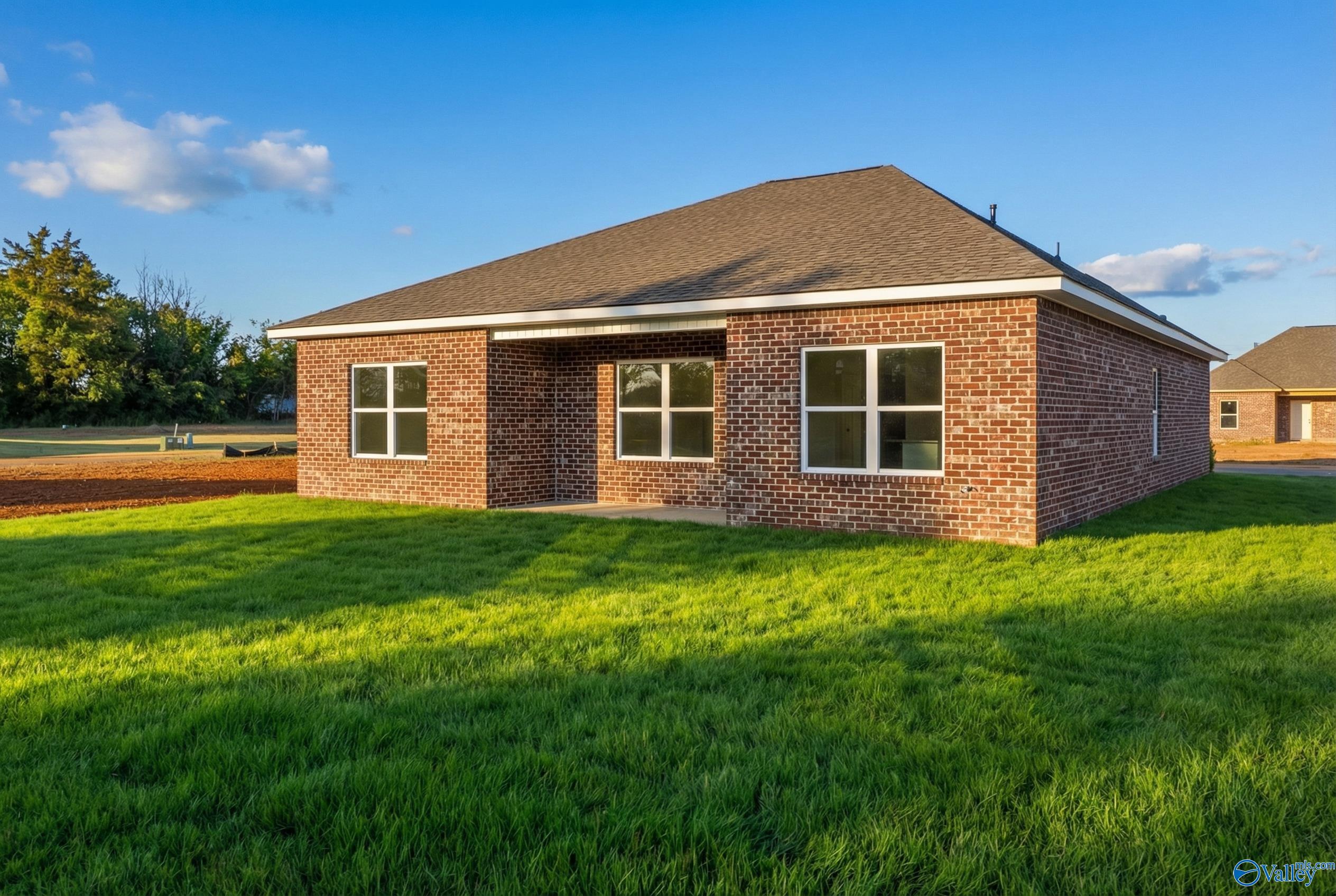 Red brick single-story home with gabled roof, large front windows, covered porch, and lush green lawn in Lynn Meadows, Meridianville, Alabama