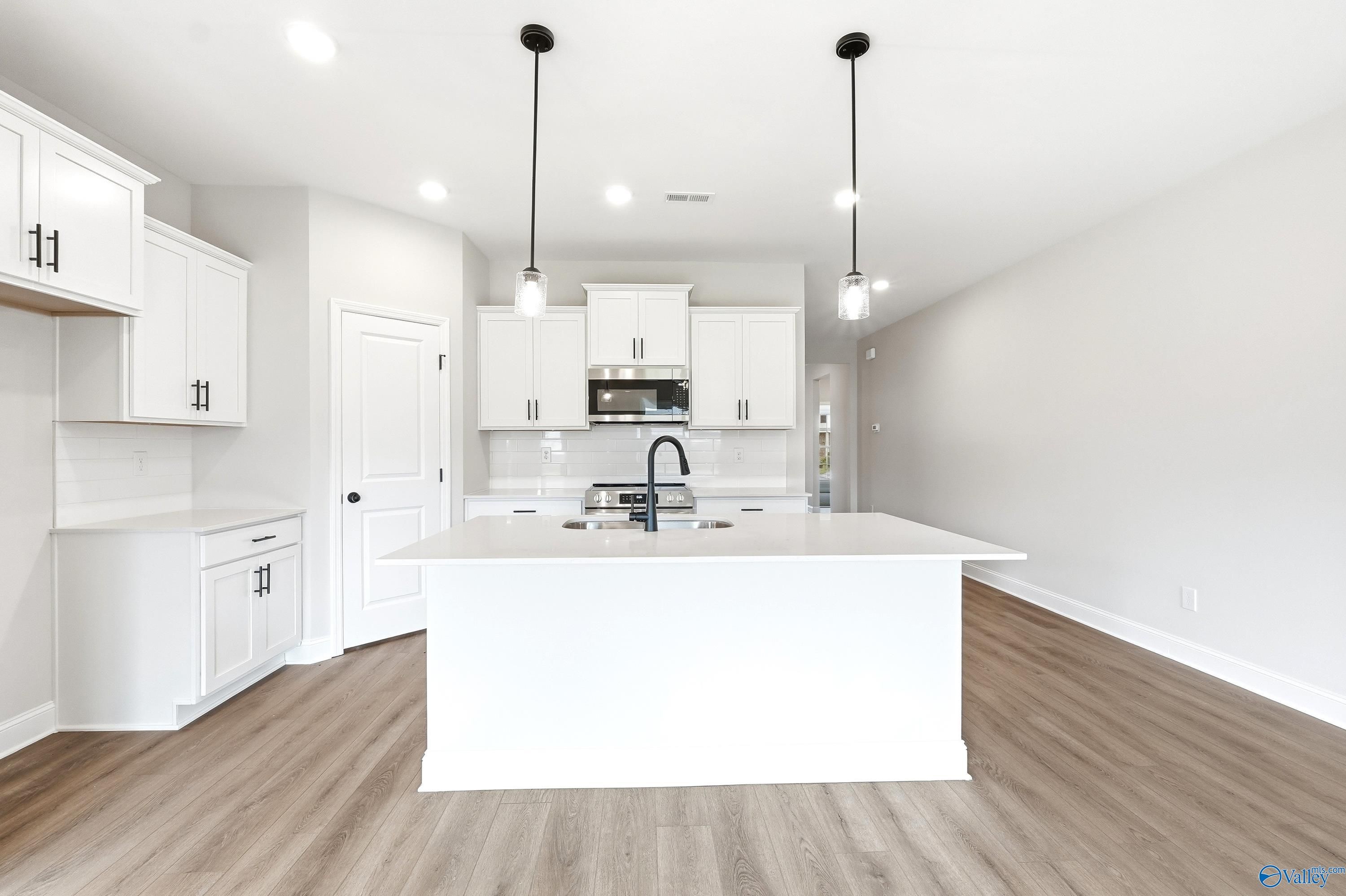 Modern kitchen with white cabinets, center island, and pendant lighting in The Daphne C floor plan at Flint Meadows.