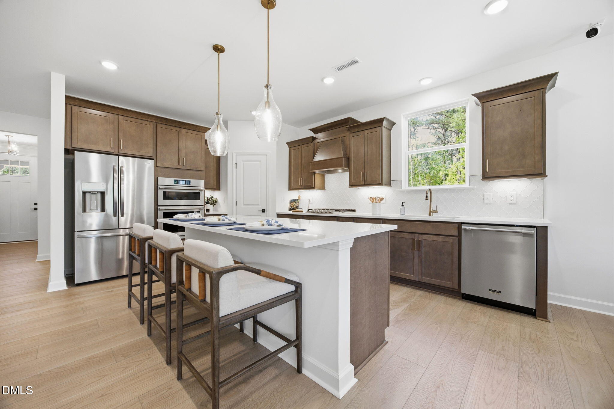 Modern kitchen with quartz island, stainless appliances, and wood cabinets in The Ashport M, Wendell Ridge, North Carolina.