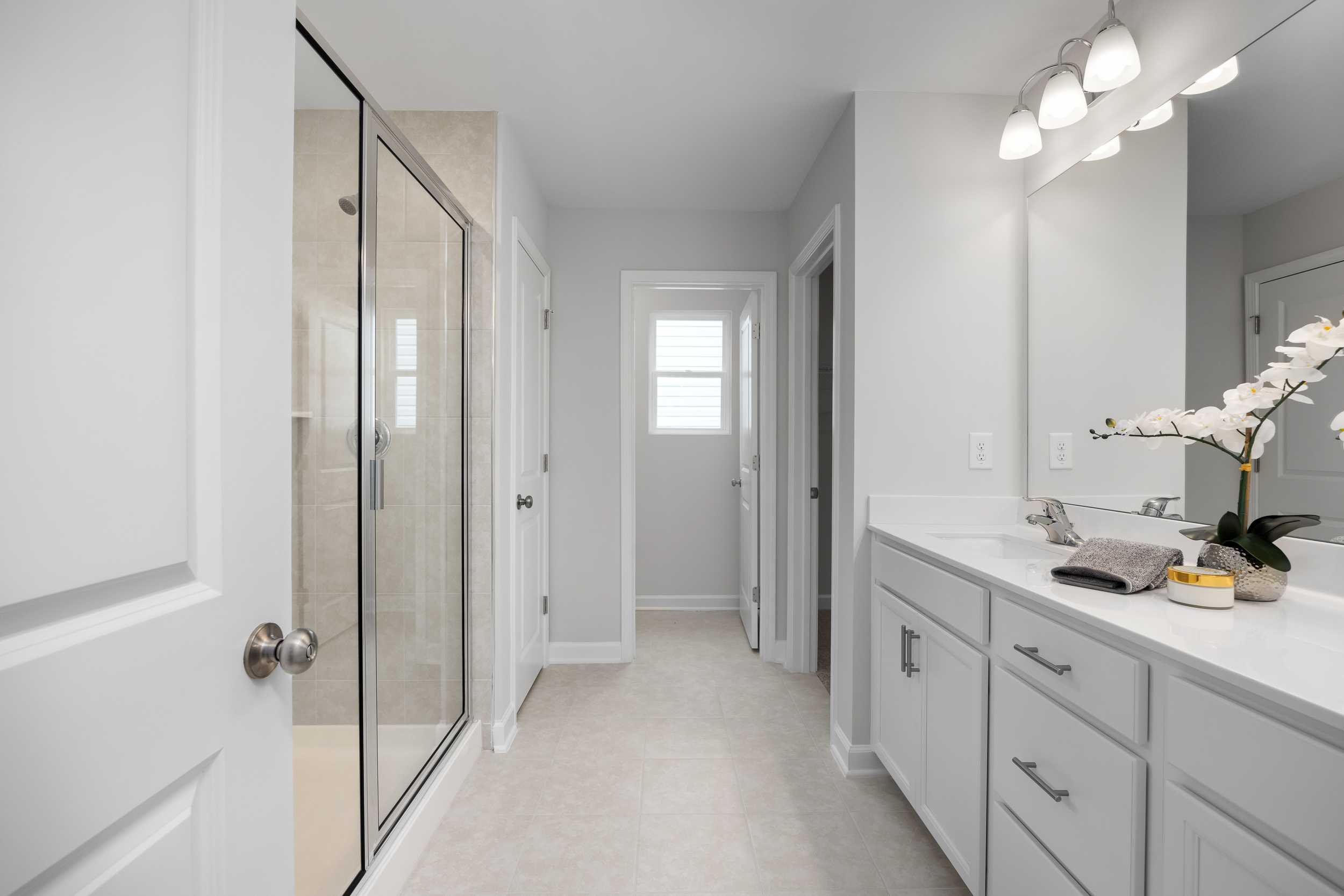 Spacious primary bathroom at Gregory Village Townhomes in Lillington NC with glass shower, double vanity, and orchid accents