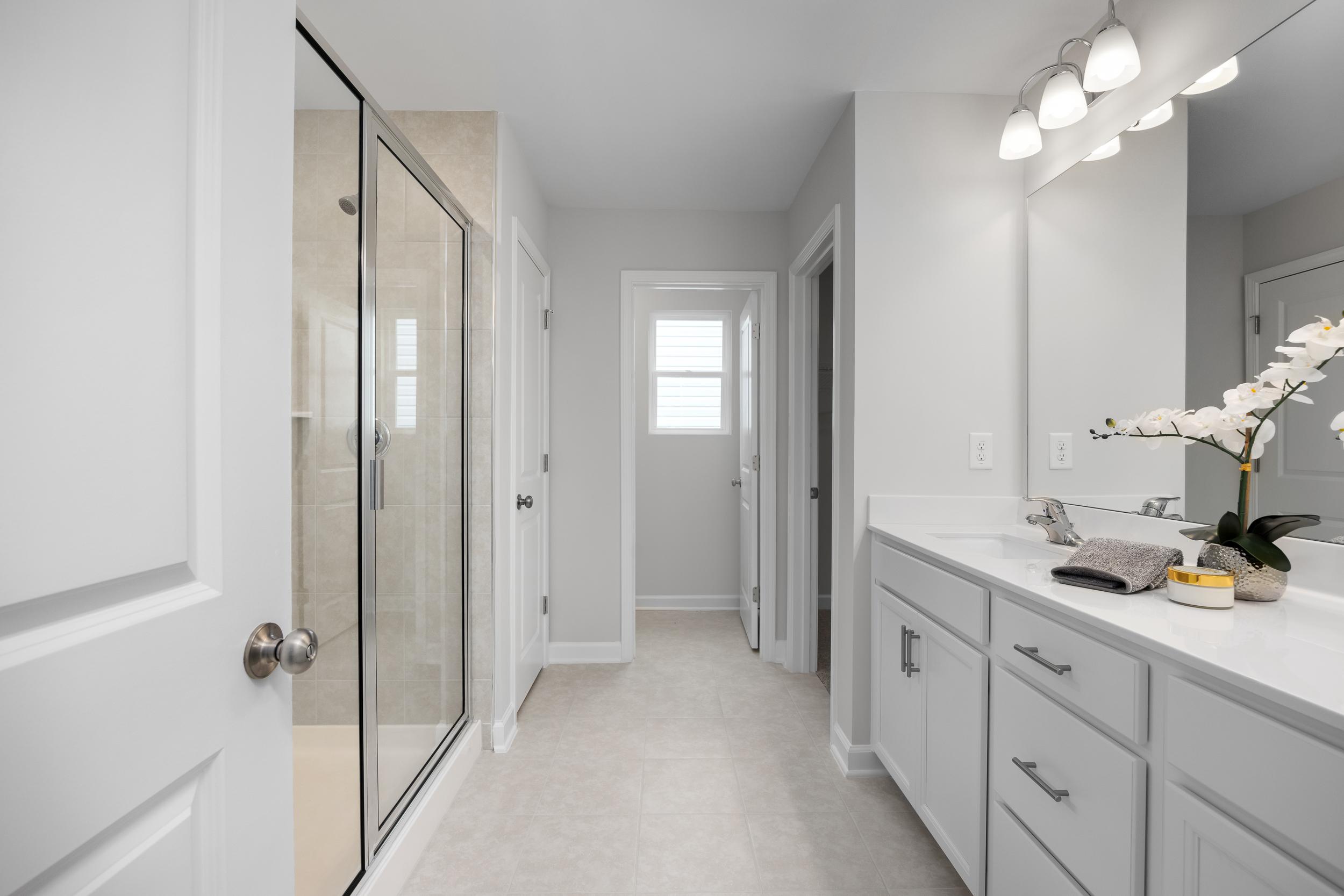 Spacious primary bathroom at Gregory Village Townhomes in Lillington NC with glass shower, double vanity, and orchid accents