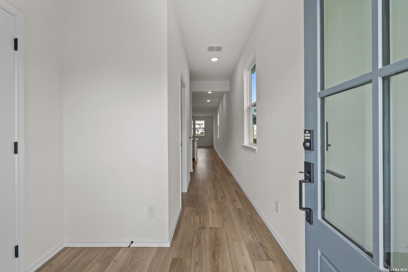 Bright entry hallway with wood-look flooring and glass-paneled front door in Davidson Homes The Summit B, Morgan Meadows, San Antonio