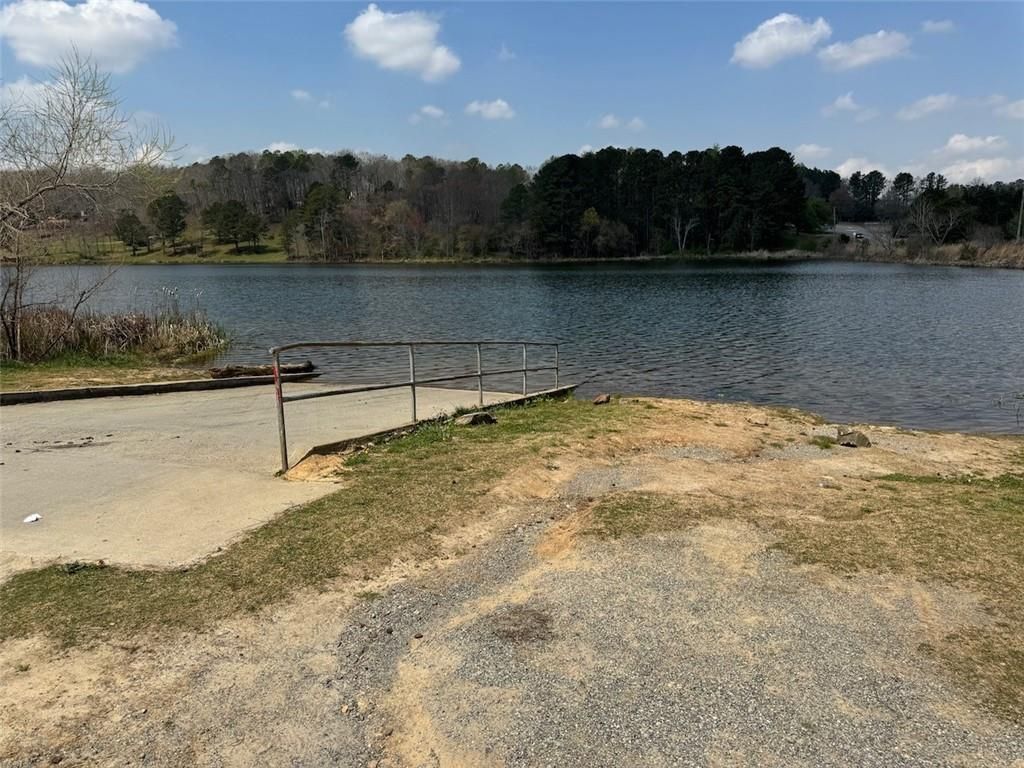 Tranquil lakefront dock with metal railing amid pine woods under blue sky in The Bluffs, Canton, Georgia