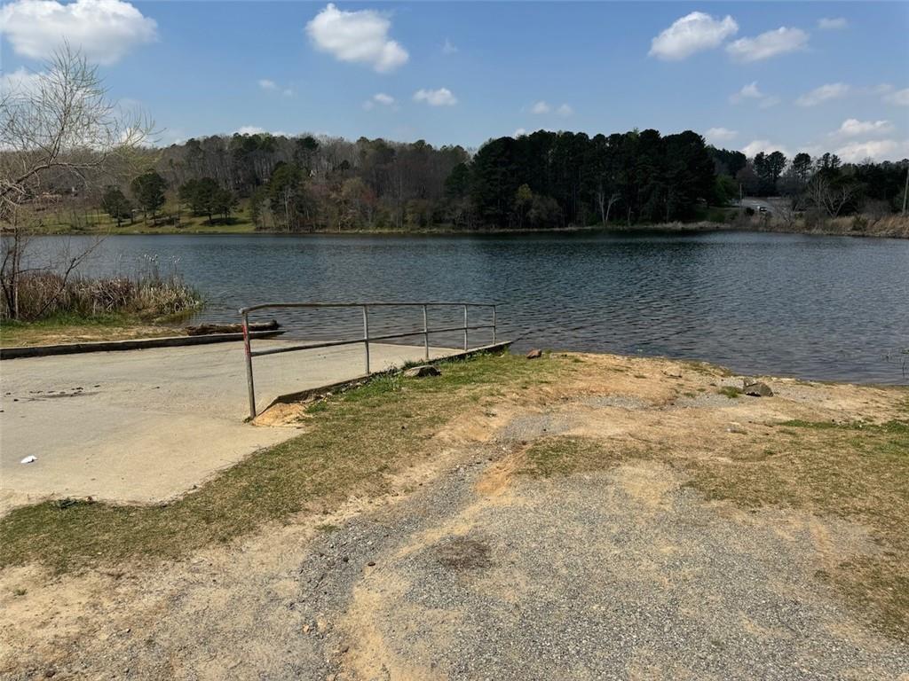 Tranquil lakefront dock with metal railing amid pine woods under blue sky in The Bluffs, Canton, Georgia