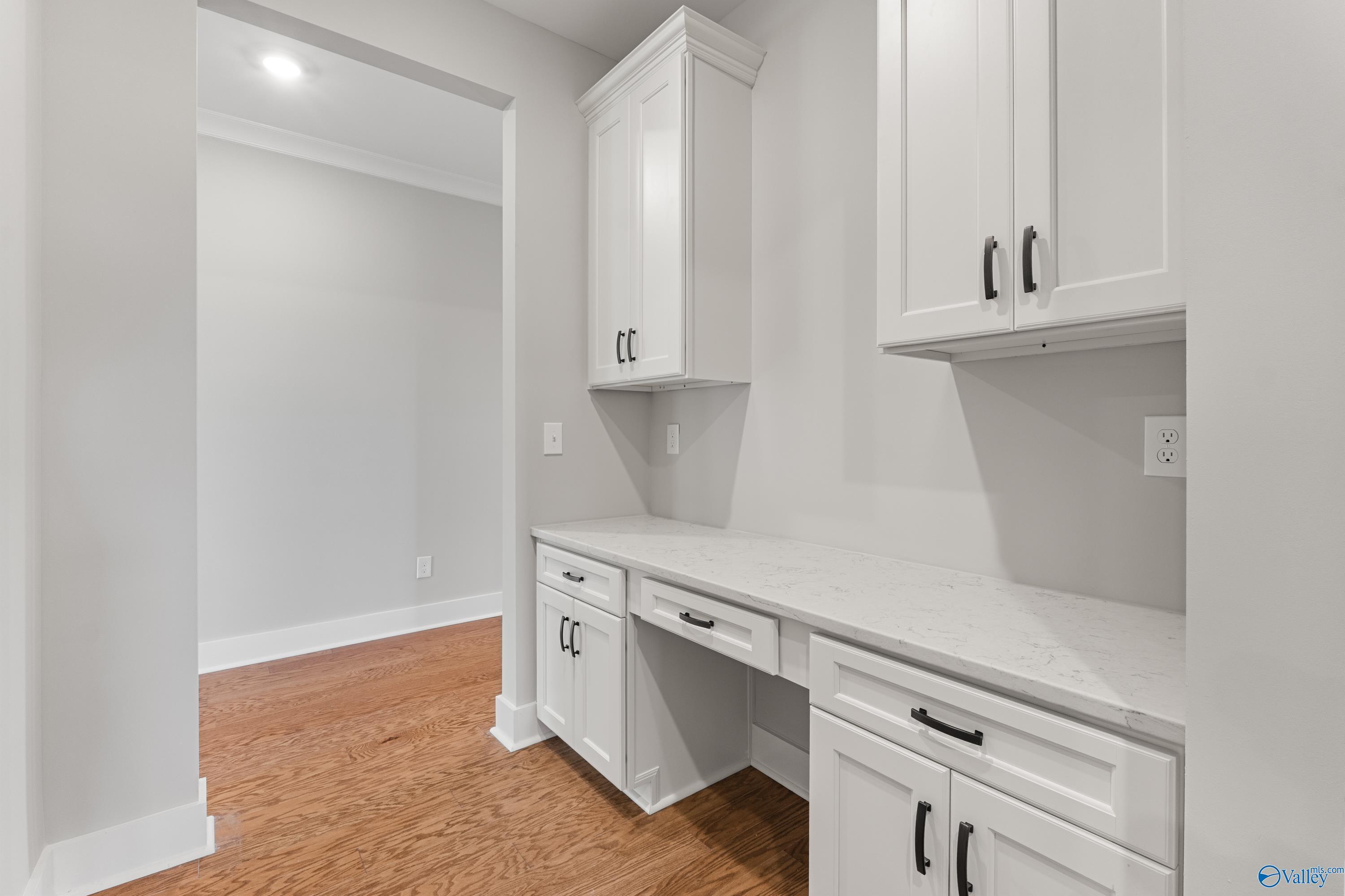 Bright butler's pantry with white shaker cabinets, quartz countertop, and built-in desk in Davidson Homes The Arcadia, Huntsville