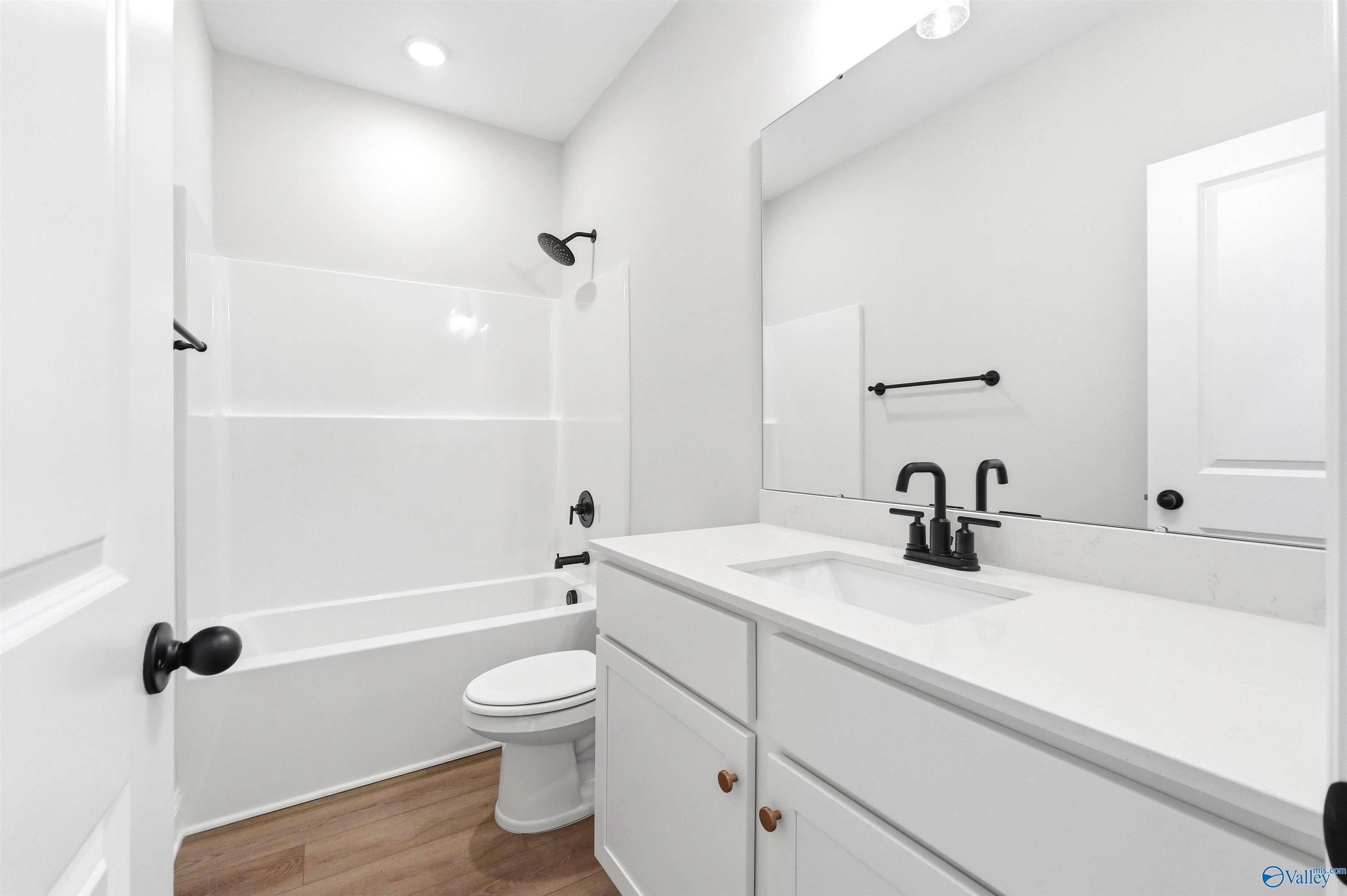 Modern bathroom with white vanity, matte black fixtures, and tub-shower combo in The Daphne F home at Berry Cove, Alabama.