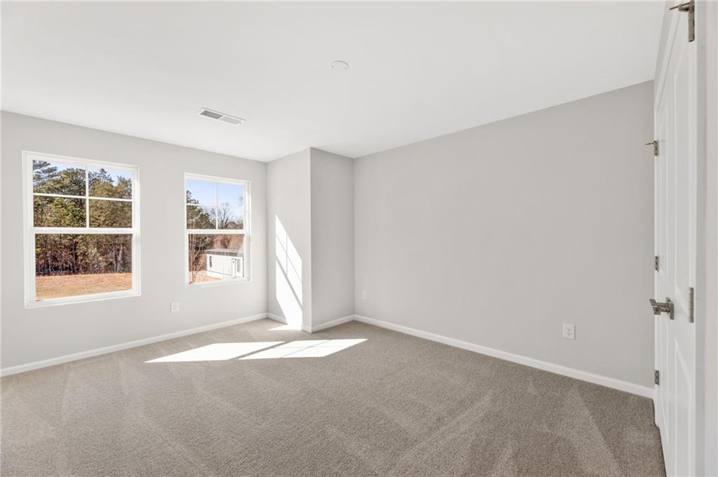 Bright bedroom with light gray walls, carpeted floor, and large sunny windows in Davidson Homes Marion A, Winder, Georgia