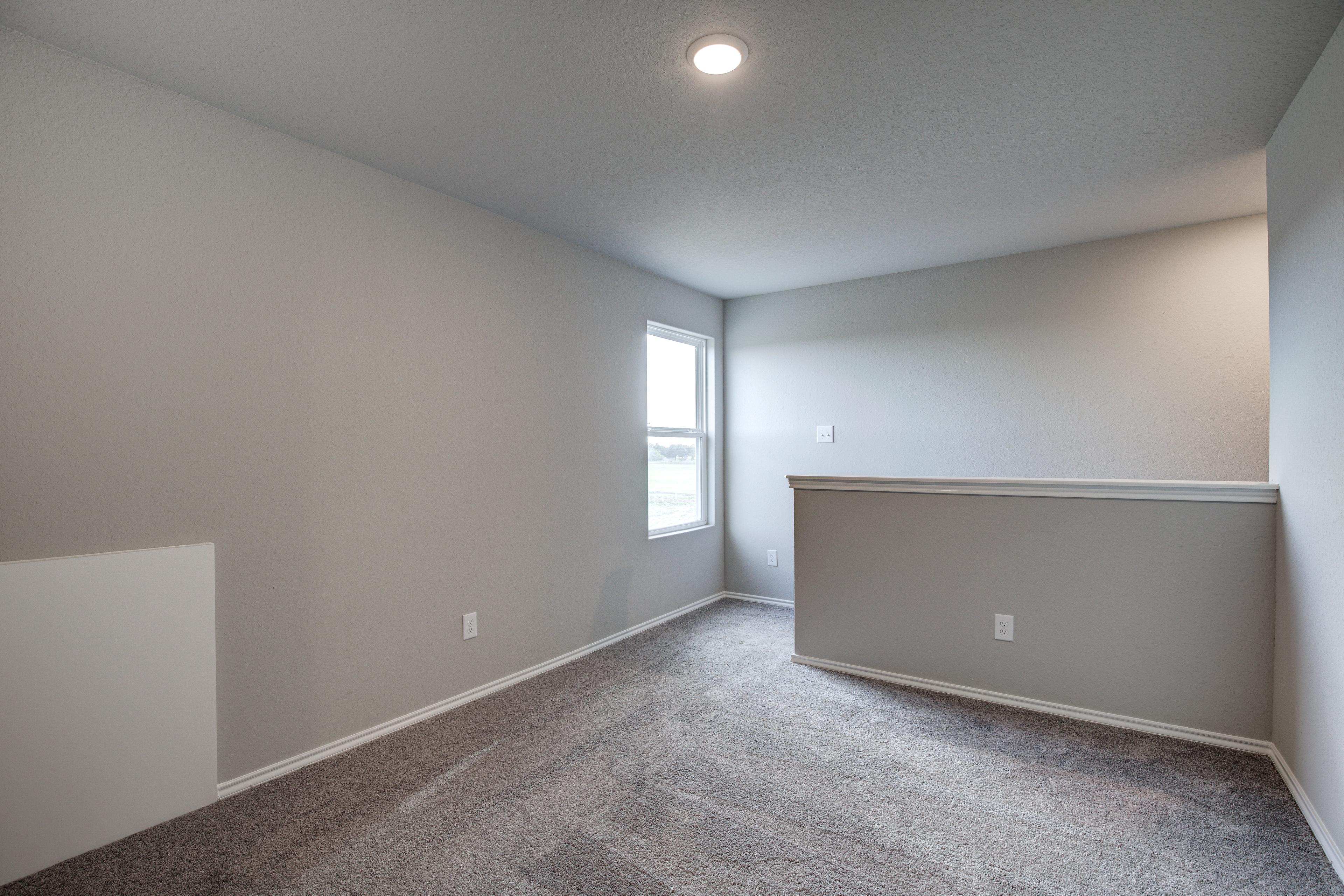 Spacious empty bedroom in The Blanco C with light gray walls, beige carpet, large window, and balcony railing overlook