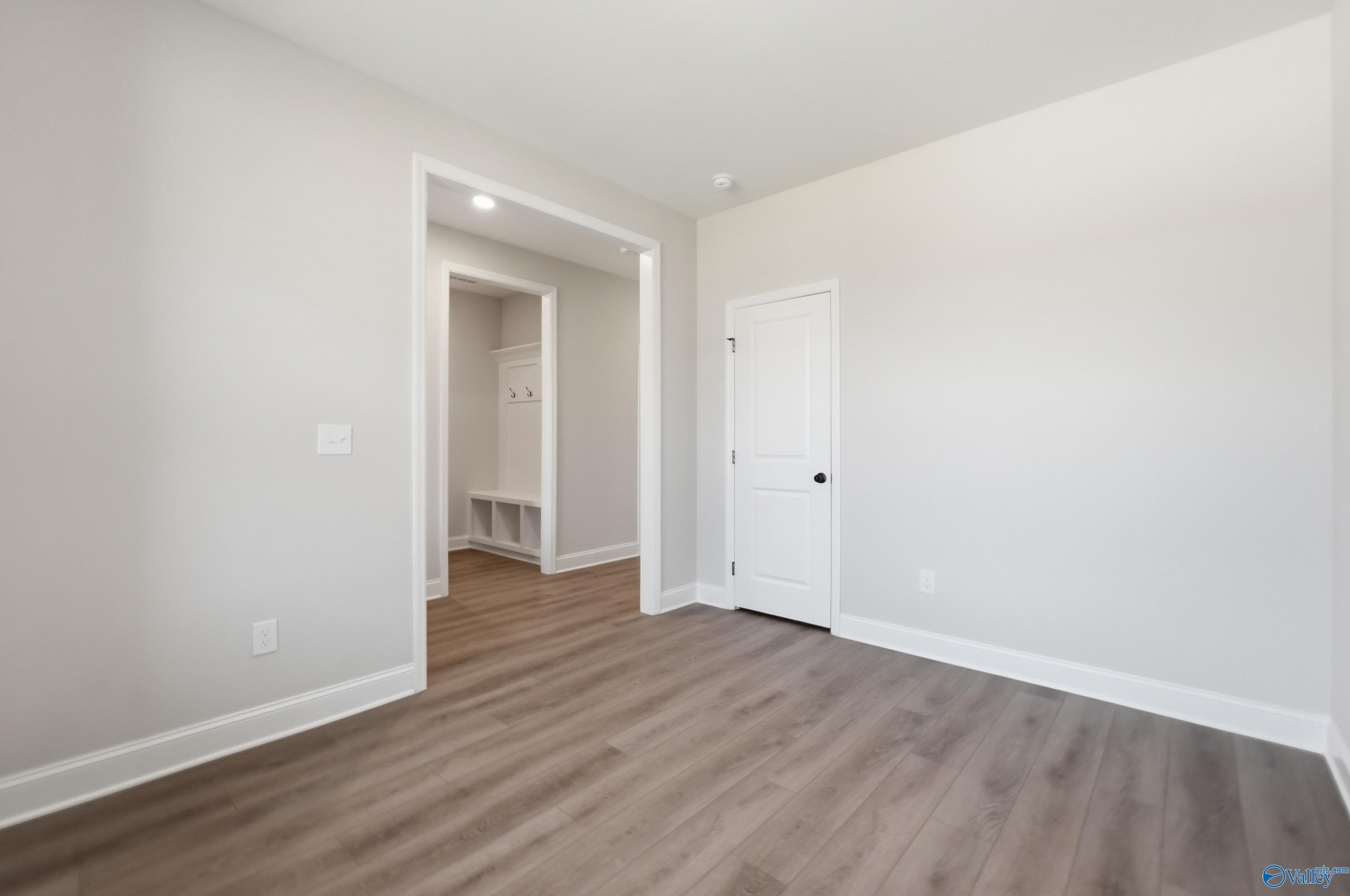 Bright bedroom with light gray walls, luxury vinyl plank floors, walk-in closet shelving and bathroom door in Davidson Homes The Rockford B, Athens AL
