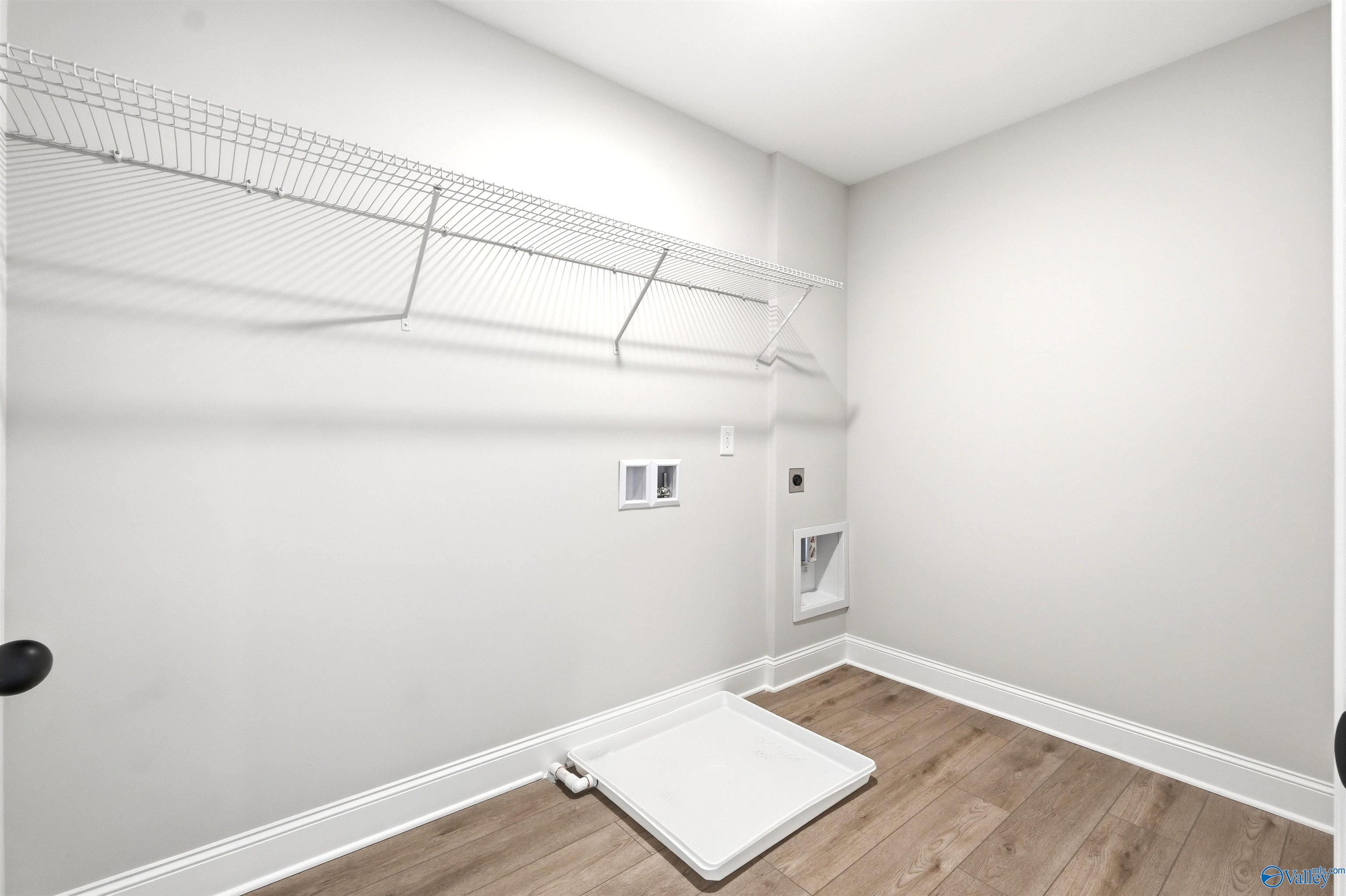Laundry room with white wire shelving and washer hookups in The Shelby A floor plan at Wood Trail in Toney, Alabama.