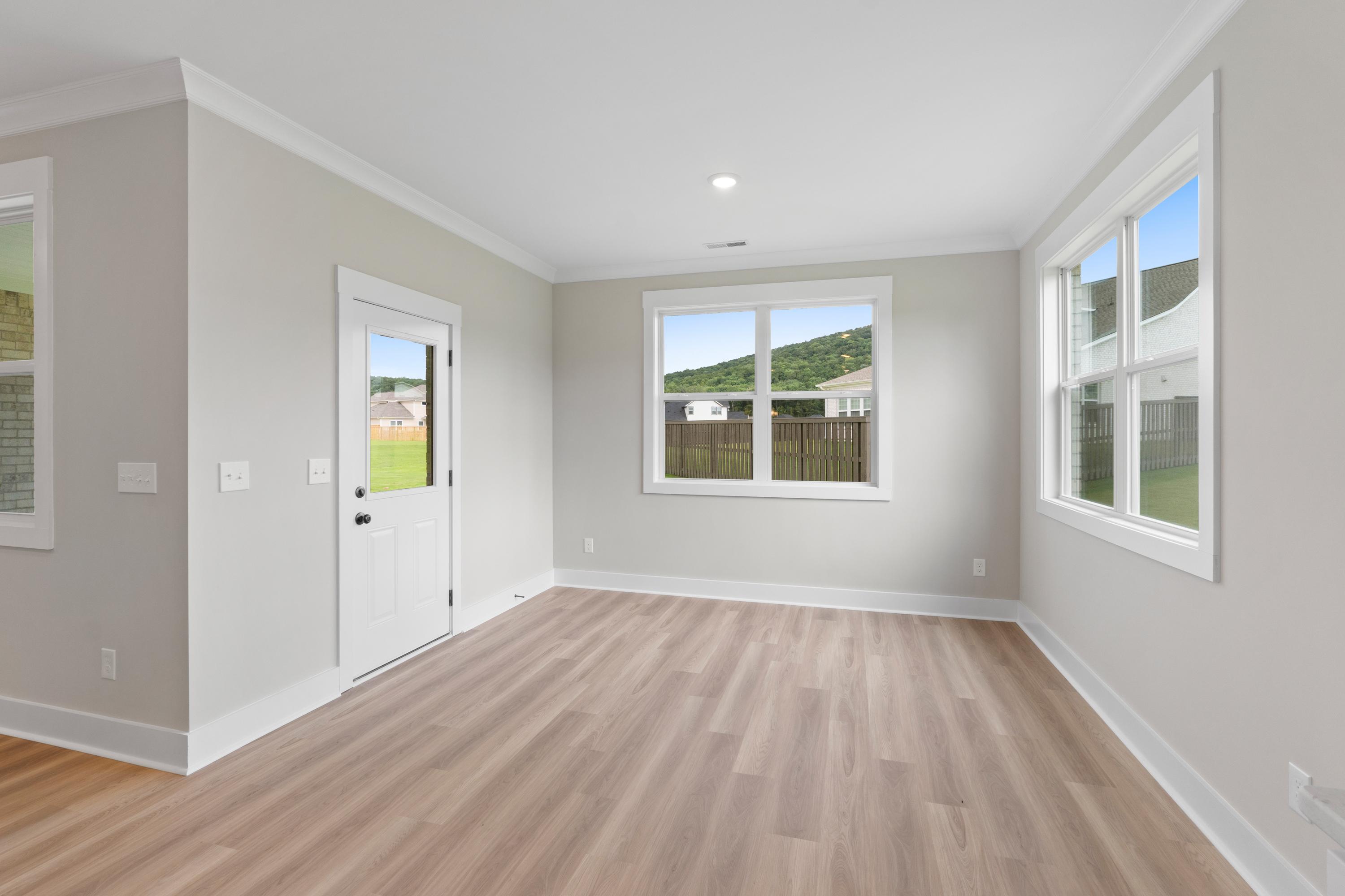 Spacious master bedroom in The Oxford with neutral walls, hardwood floors, and large windows overlooking green hills
