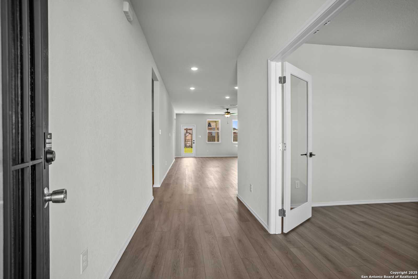 Bright hallway with light wood floors, white walls, and open glass doors in Davidson Homes The Douglas B, Converse, Texas