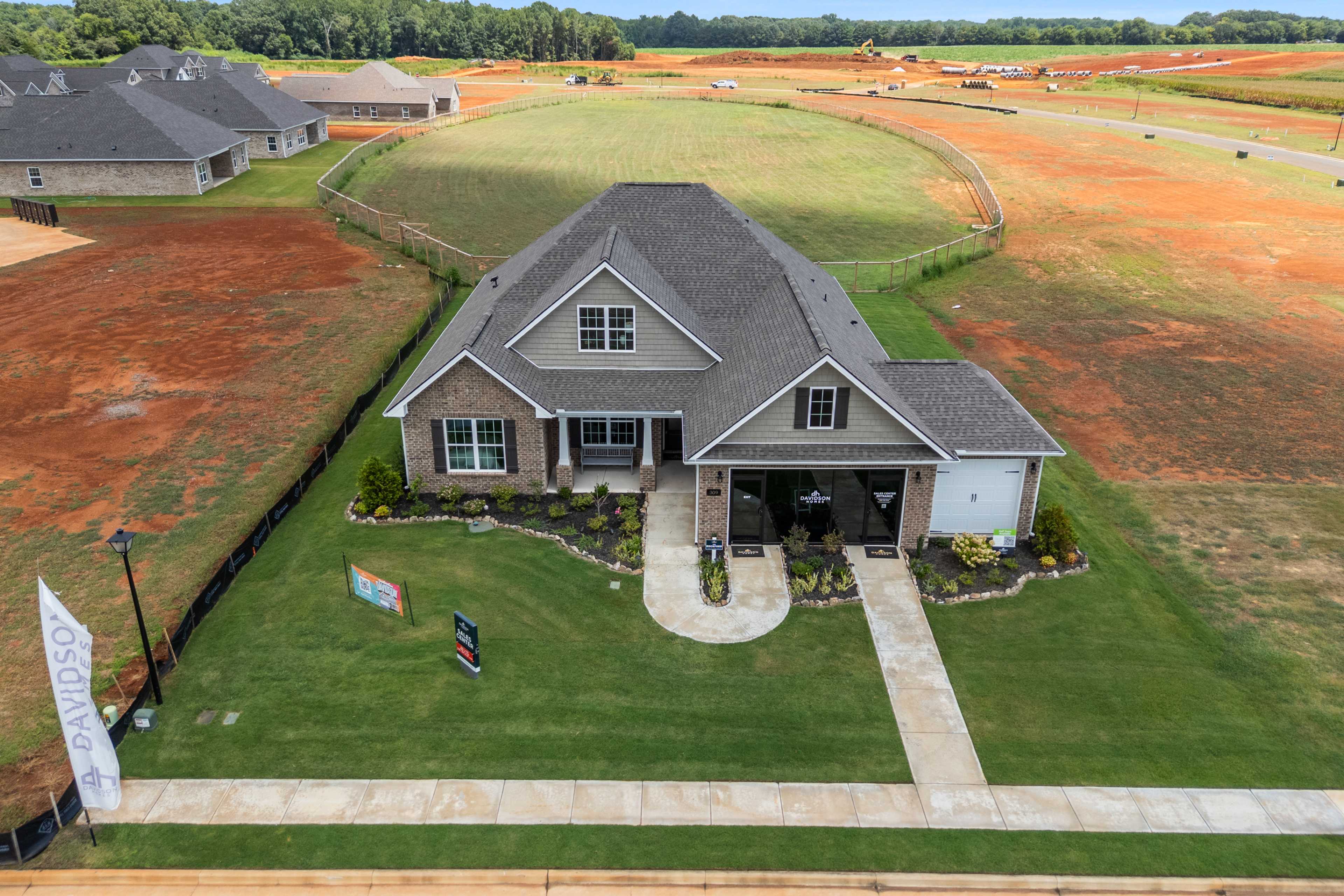 Aerial view of new craftsman home with gabled roof, covered porch, and garage at Kendall Farms in Toney Alabama amid developing neighborhood