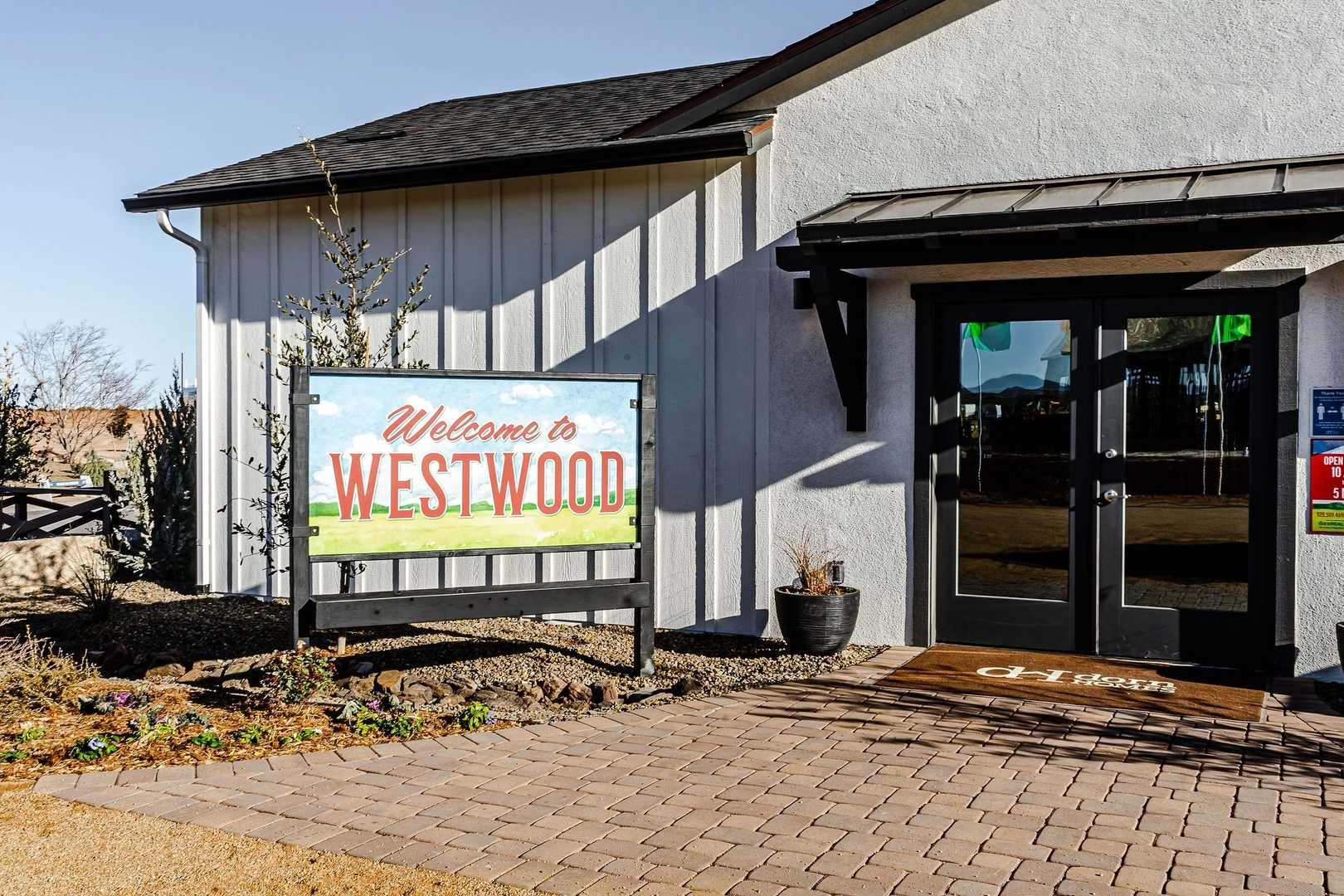 Westwood community welcome sign and modern entrance building in Prescott AZ by Davidson Homes with desert landscaping and paver walkway