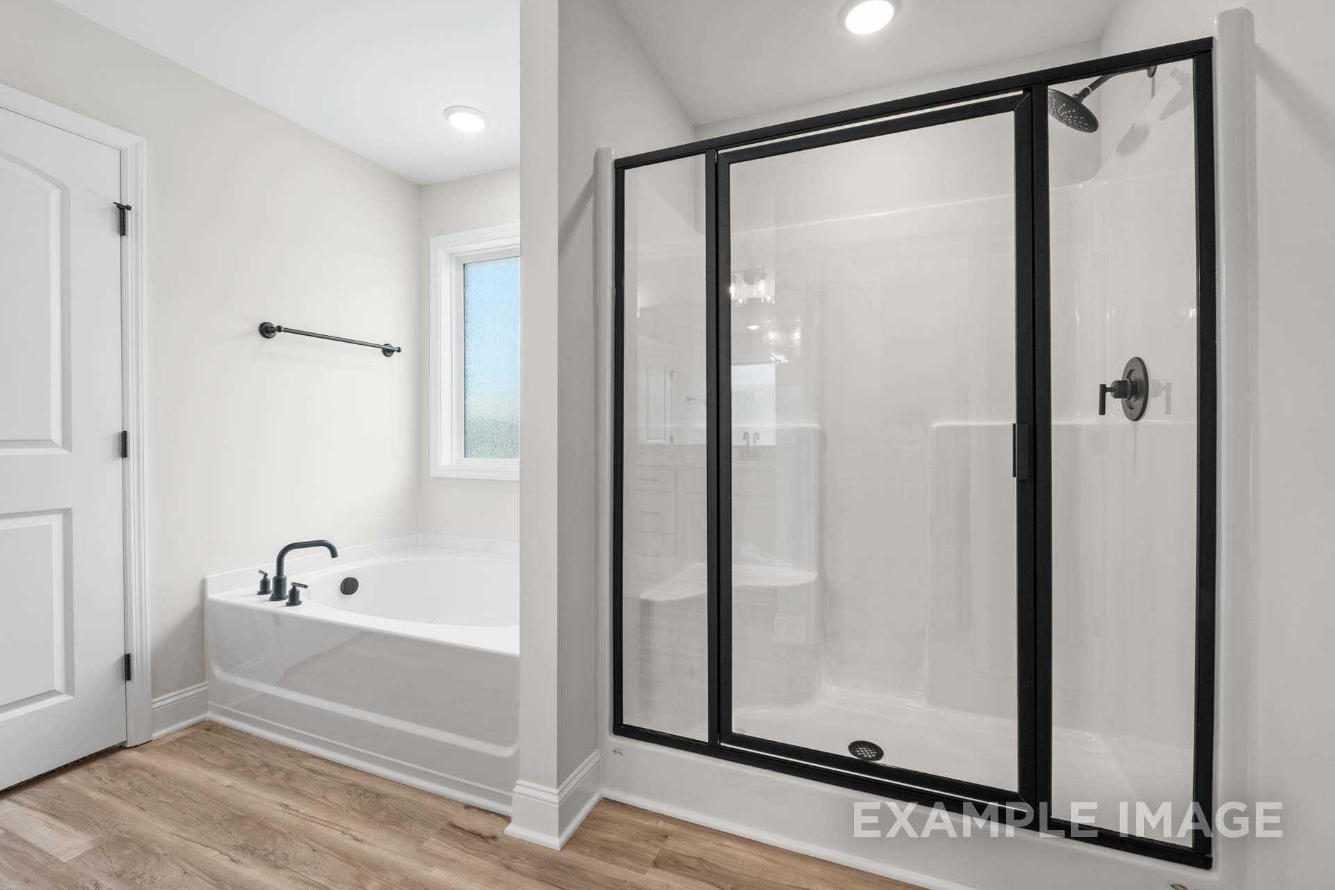 Master bathroom in The Holly home design featuring soaking tub, glass shower enclosure, and modern black fixtures
