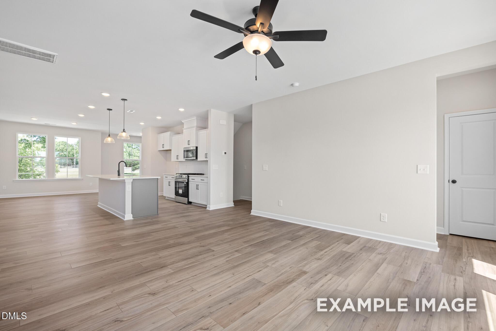 Open-concept living room and kitchen with wood flooring in The Mitchell floor plan by Davidson Homes in Camden Park.