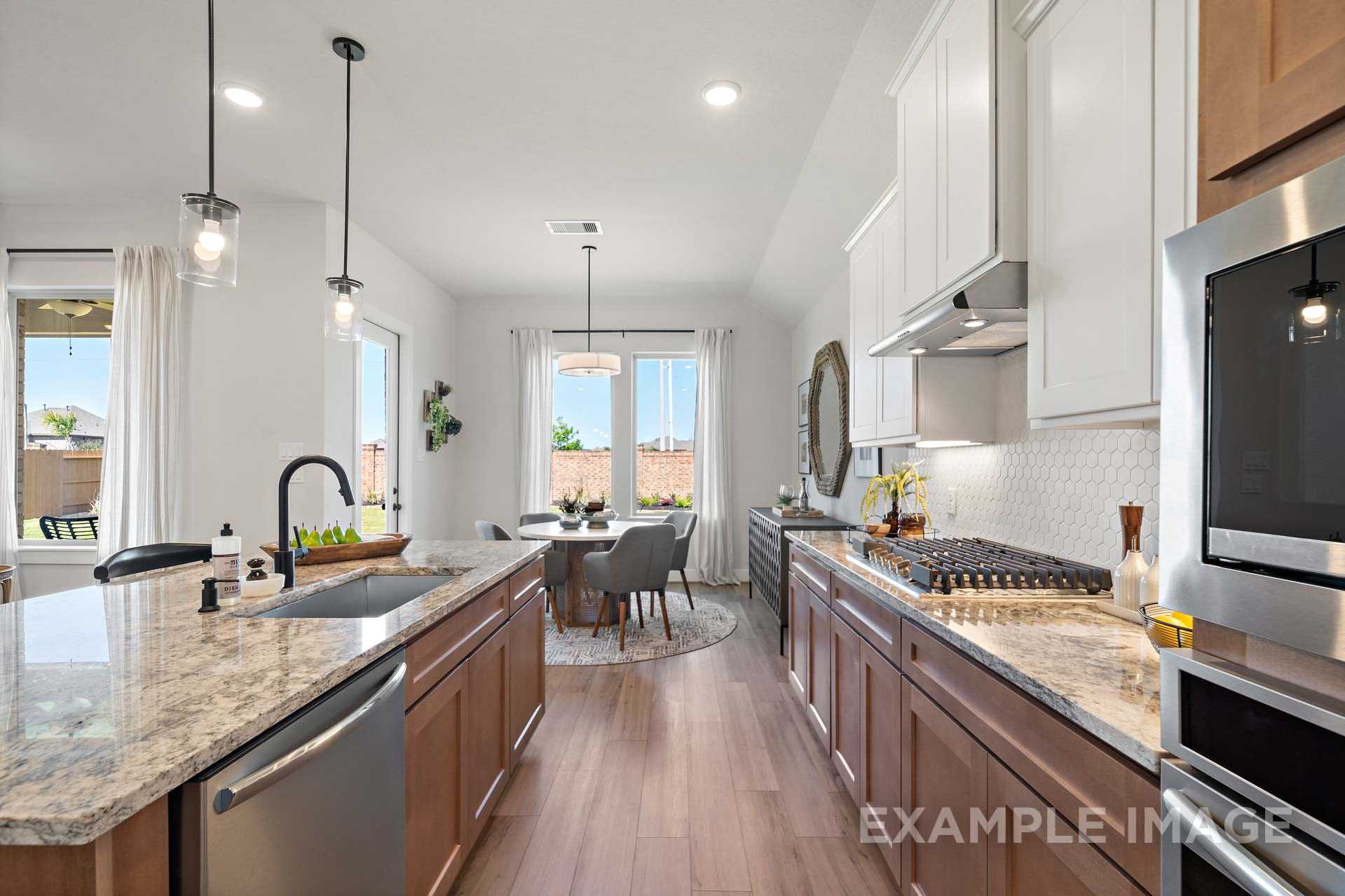 Open-concept kitchen and dining area in The Edward C with granite counters, stainless appliances, and hardwood floors