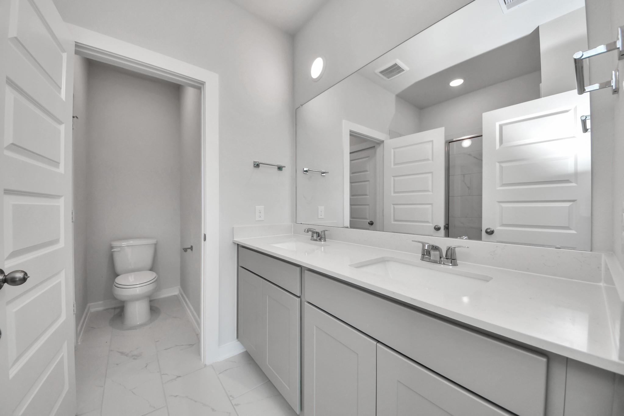 Modern bathroom with dual-sink vanity and private water closet in The Colorado G floor plan at Emberly, Beasley, Texas.