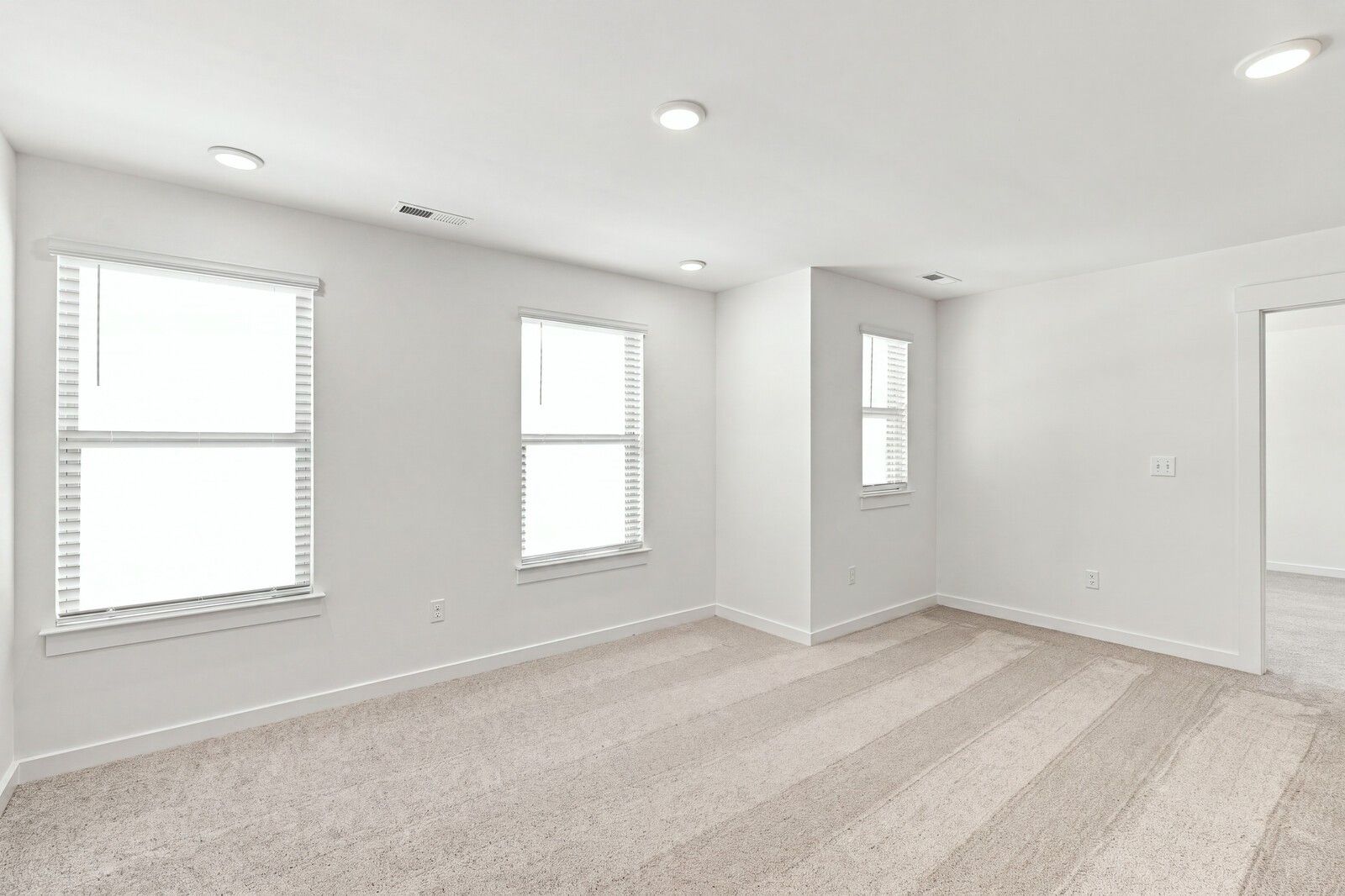 Bright carpeted bedroom with white walls and three windows in Davidson Homes The Willow C plan at Woods Crossing, Gallatin, TN