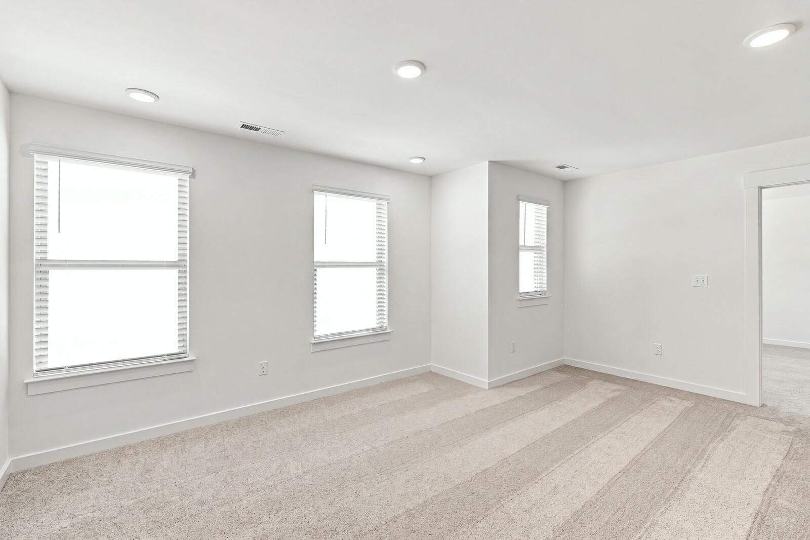 Bright carpeted bedroom with white walls and three windows in Davidson Homes The Willow C plan at Woods Crossing, Gallatin, TN