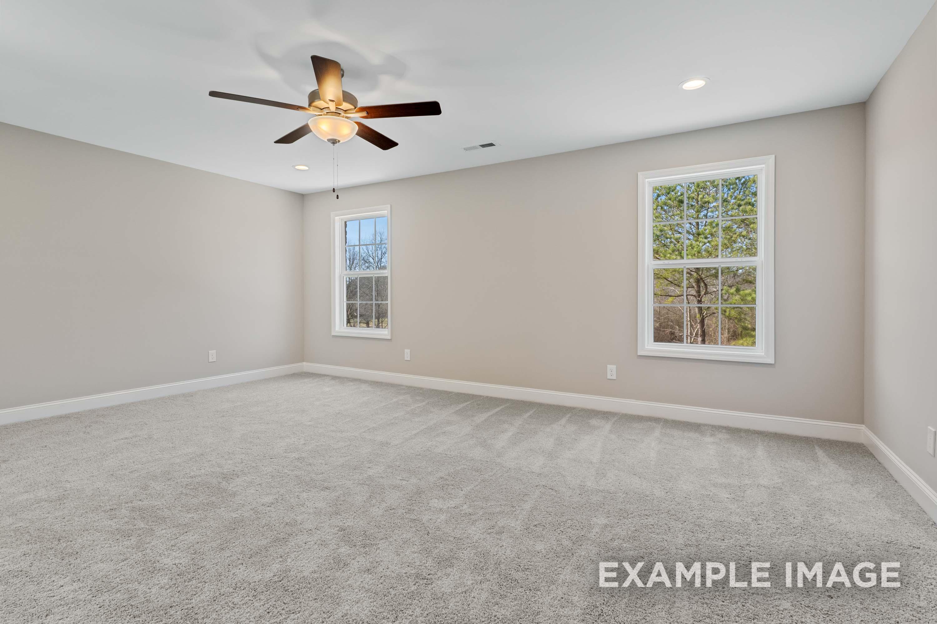 Spacious upstairs master bedroom in The Madison B with beige carpet, ceiling fan, recessed lights, and large windows overlooking trees