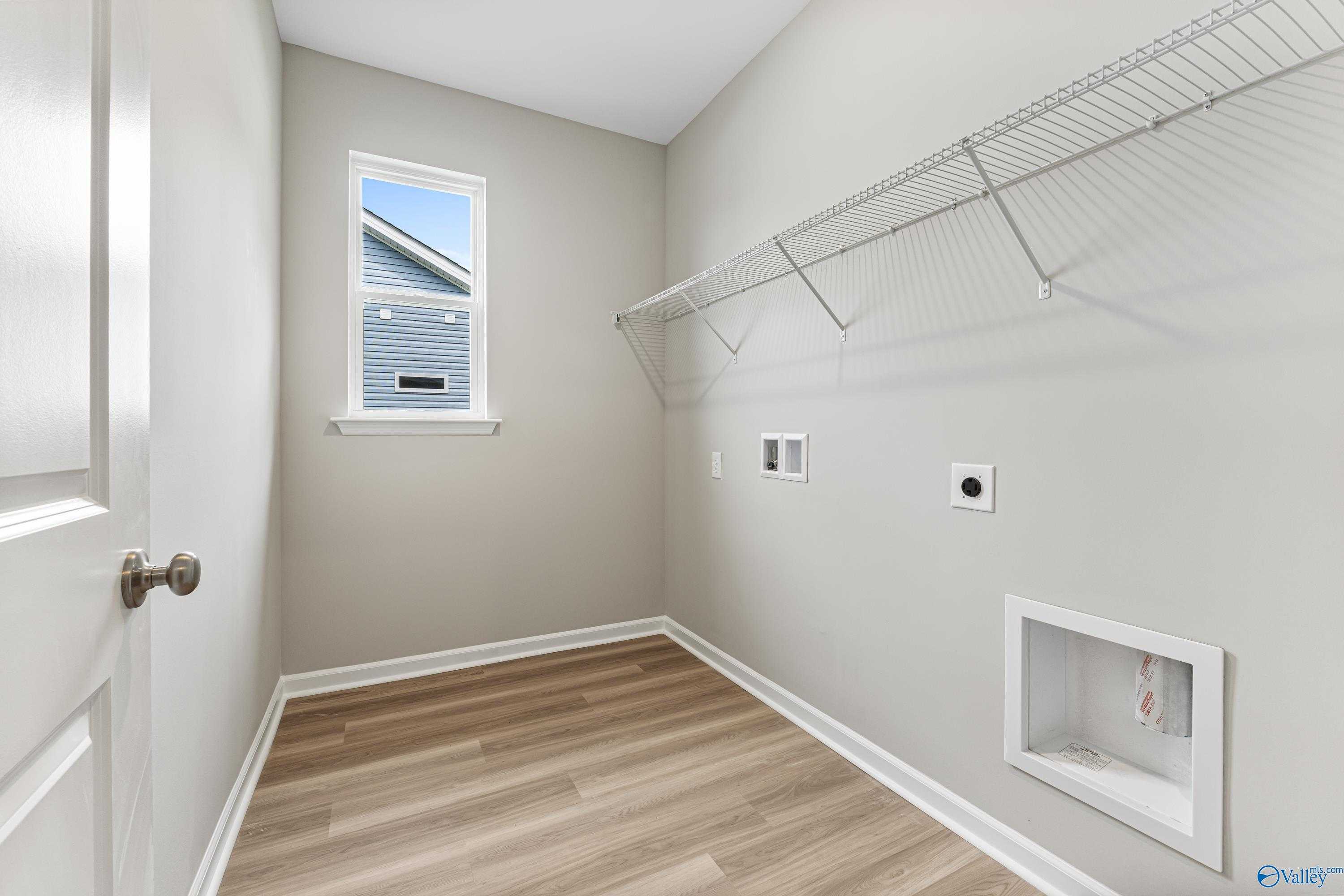 Bright laundry room with wire shelving, utility sink, outlets, and window in Davidson Homes The Aurora, Fayetteville, Tennessee