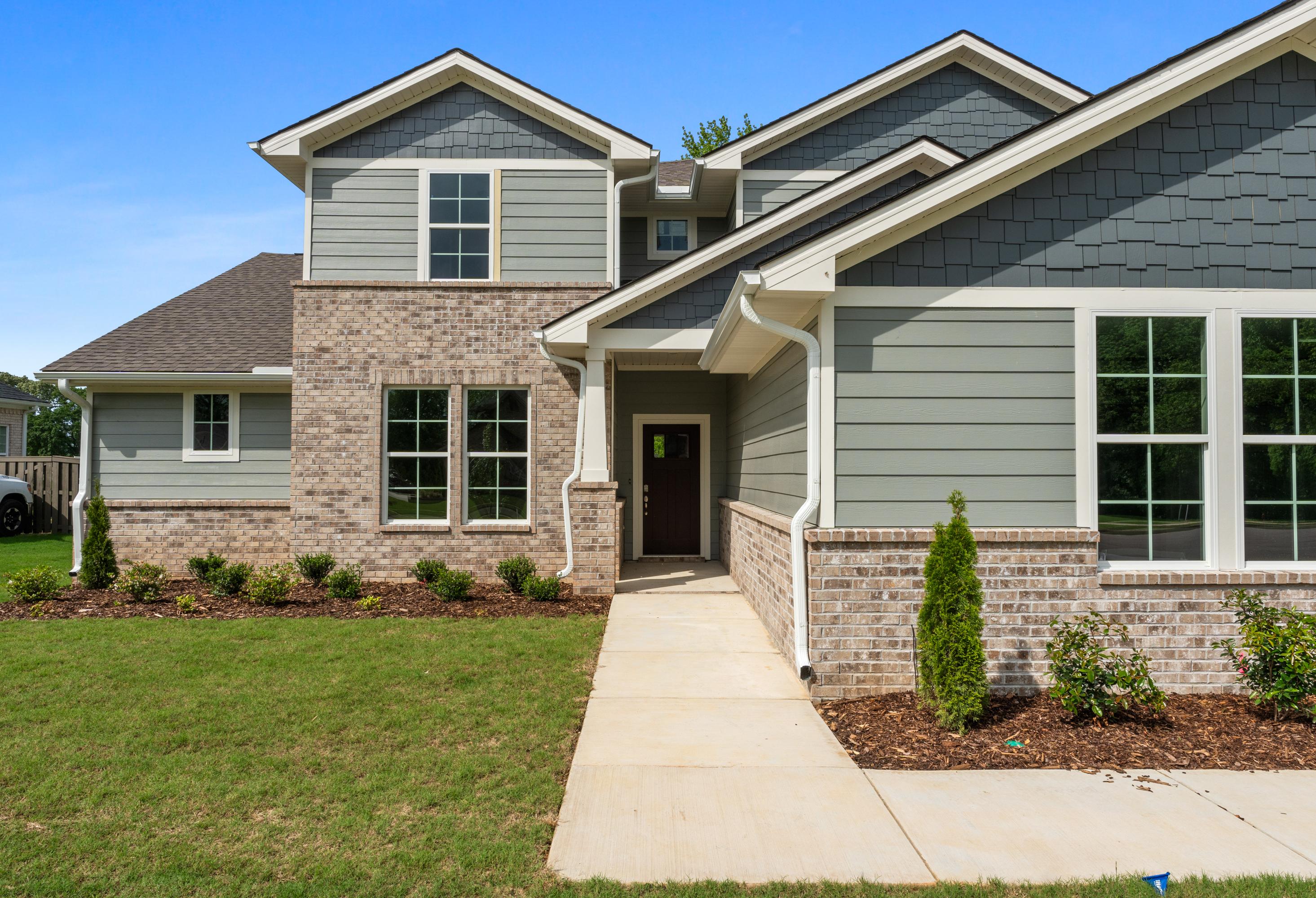 Two-story Avalon D home elevation with gray siding, brick accents, covered porch, and three-car garage in Owens Cross Roads