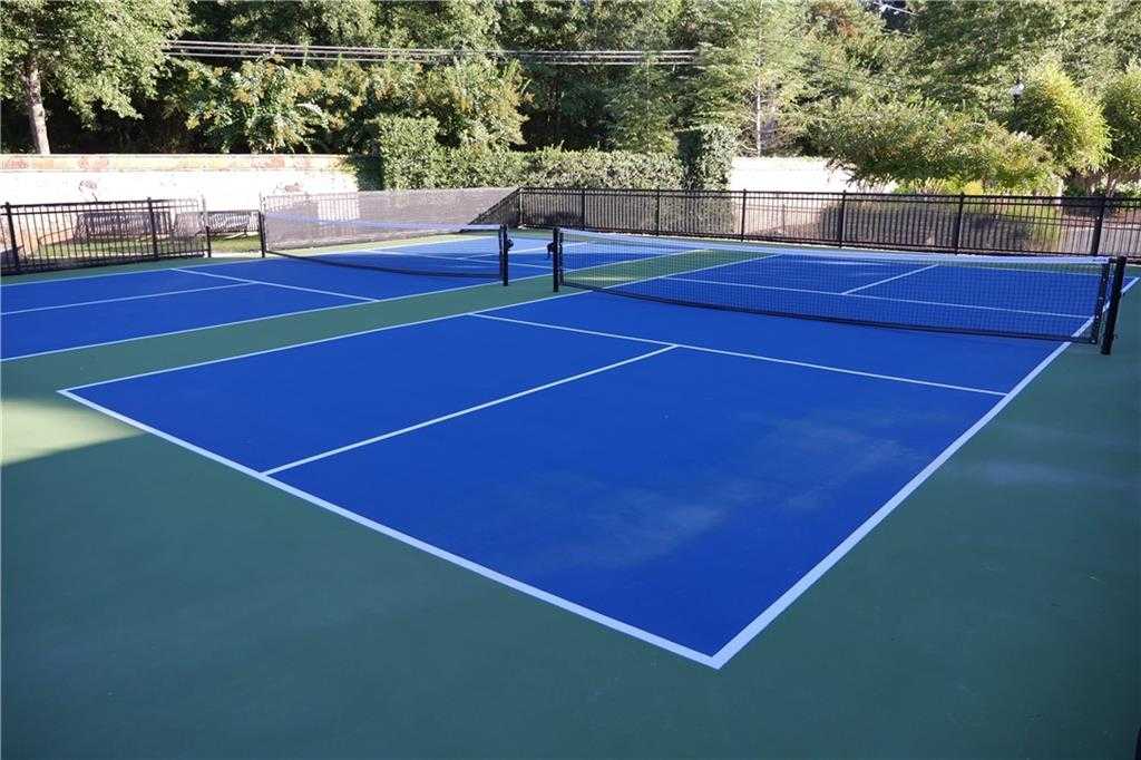 Community tennis courts with blue surfaces, nets, and lush greenery in The Village at Towne Lake, Woodstock, Georgia