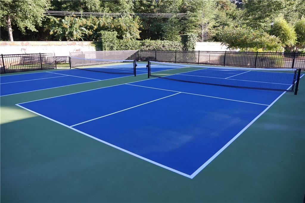 Community tennis courts with blue surfaces, nets, and lush greenery in The Village at Towne Lake, Woodstock, Georgia