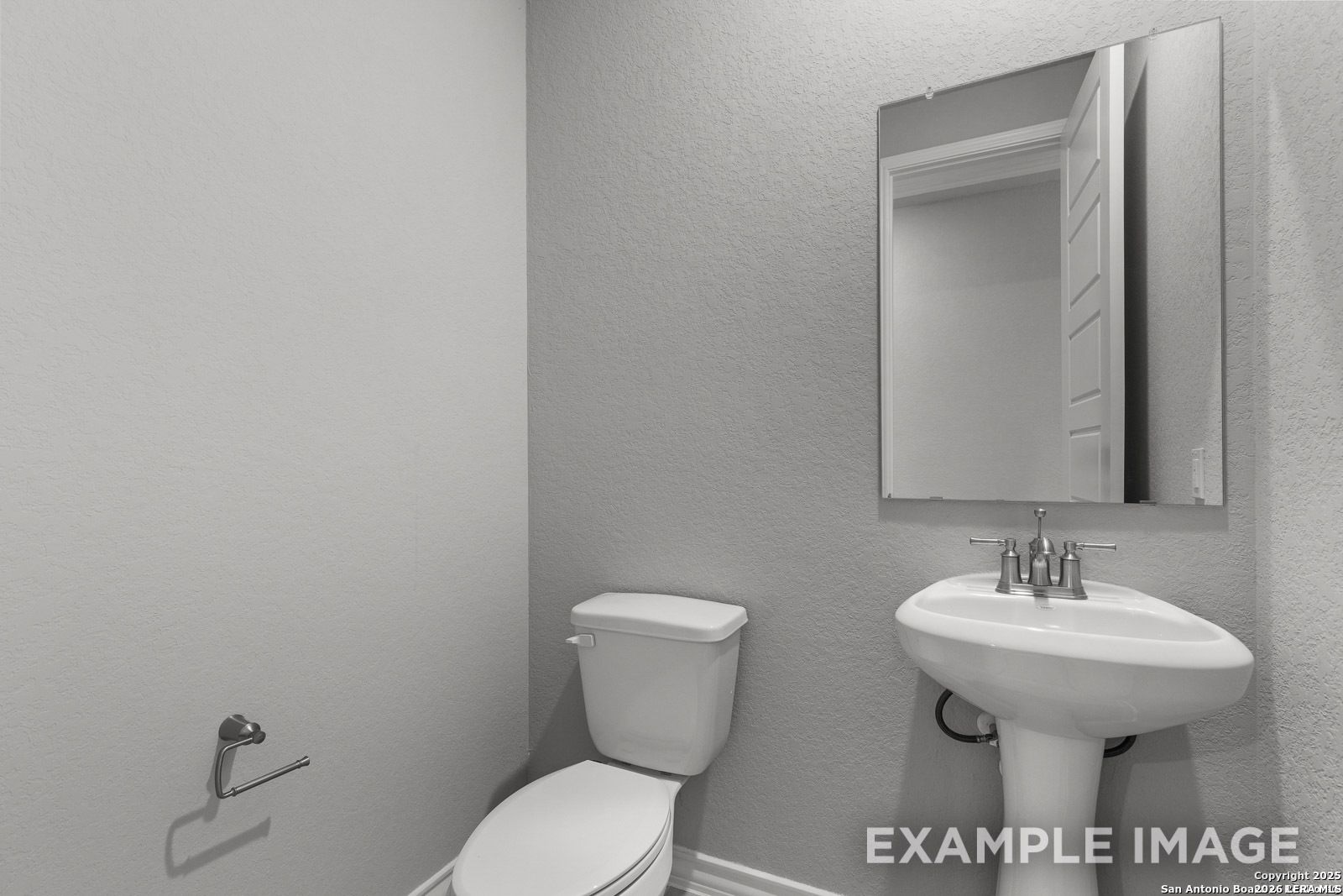 Modern half-bath with pedestal sink and wall mirror in The Oxford F floor plan by Davidson Homes in Castroville, Texas.