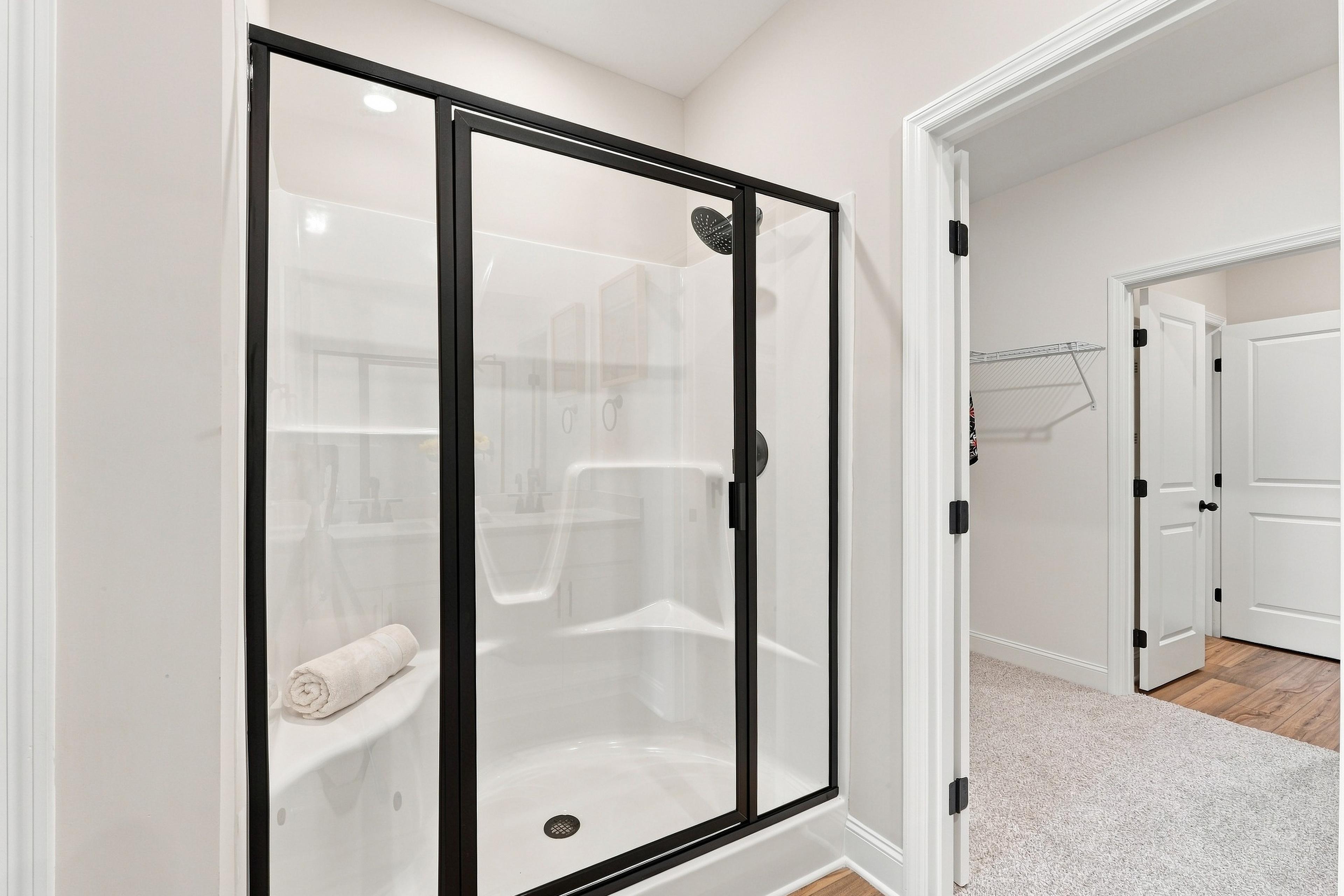 Glass-enclosed shower with black frame in primary bathroom at Bailey Park by Davidson Homes in Fayetteville, Tennessee