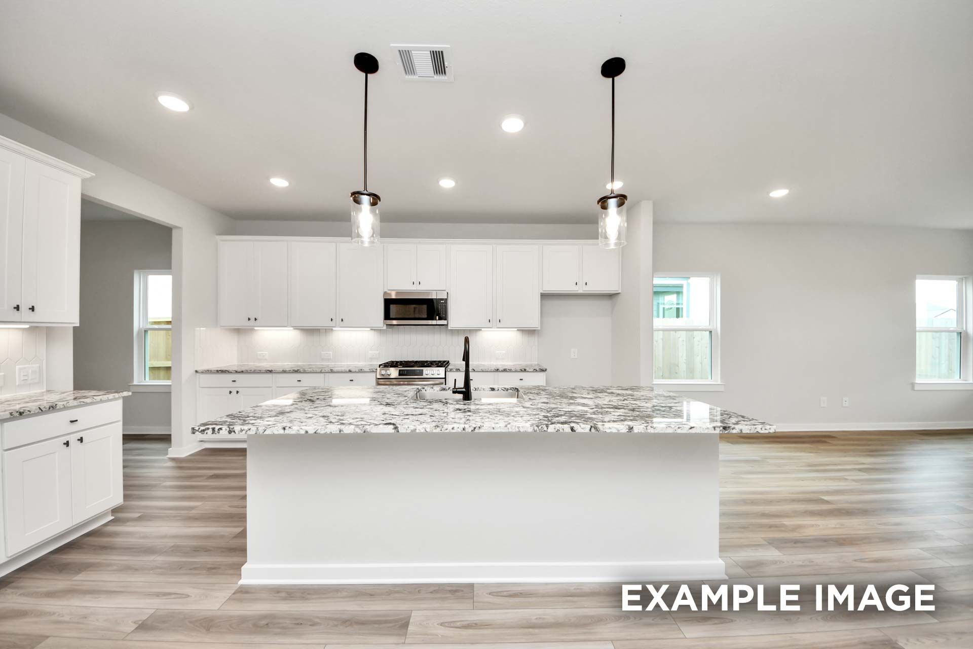 Modern kitchen in The Sorrento featuring a large granite island, white cabinets, and open-concept living in Crosby, Texas.