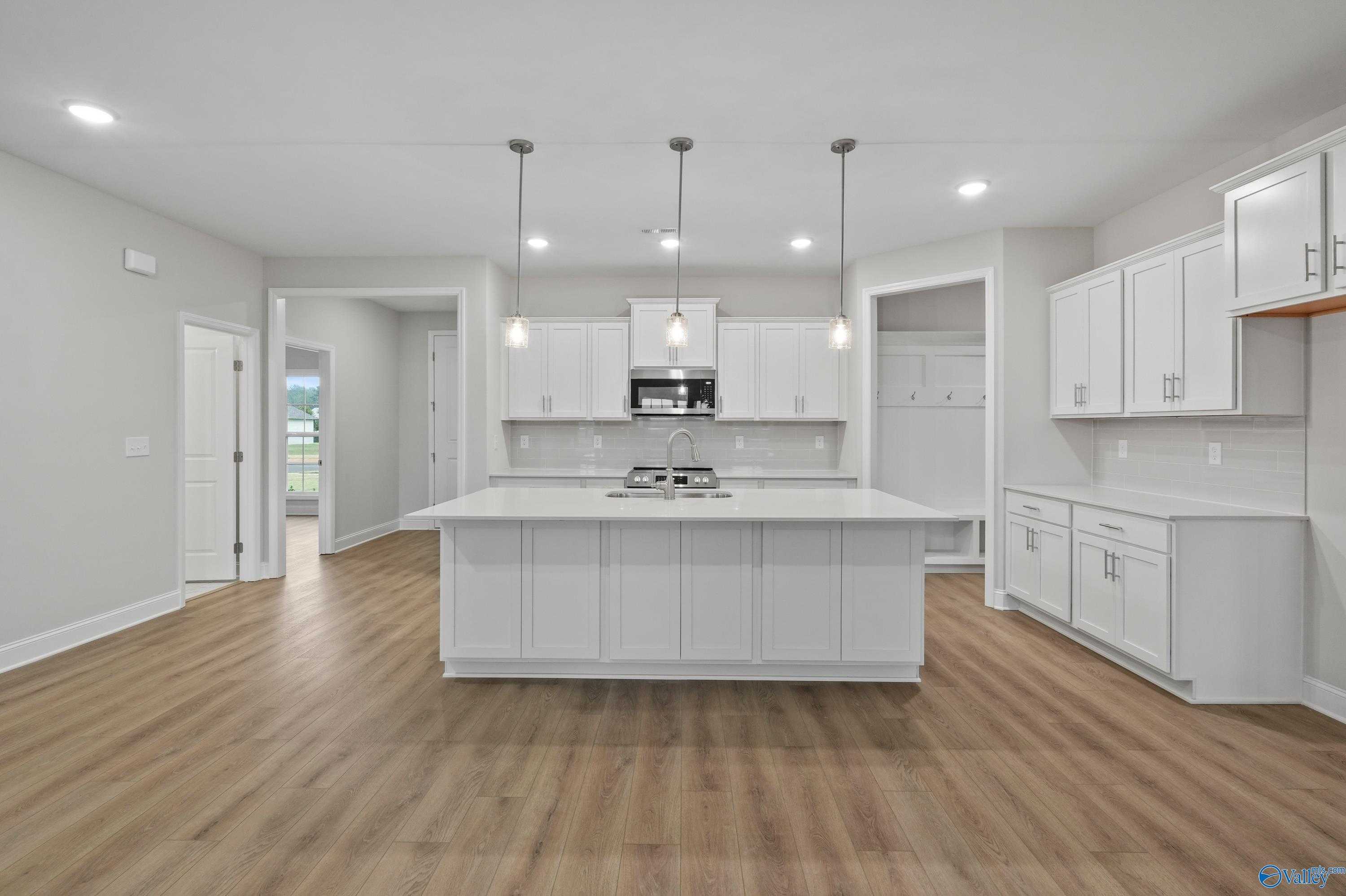 Modern white kitchen with large island, stainless steel appliances in The Lanier floor plan by Davidson Homes, Harvest, AL