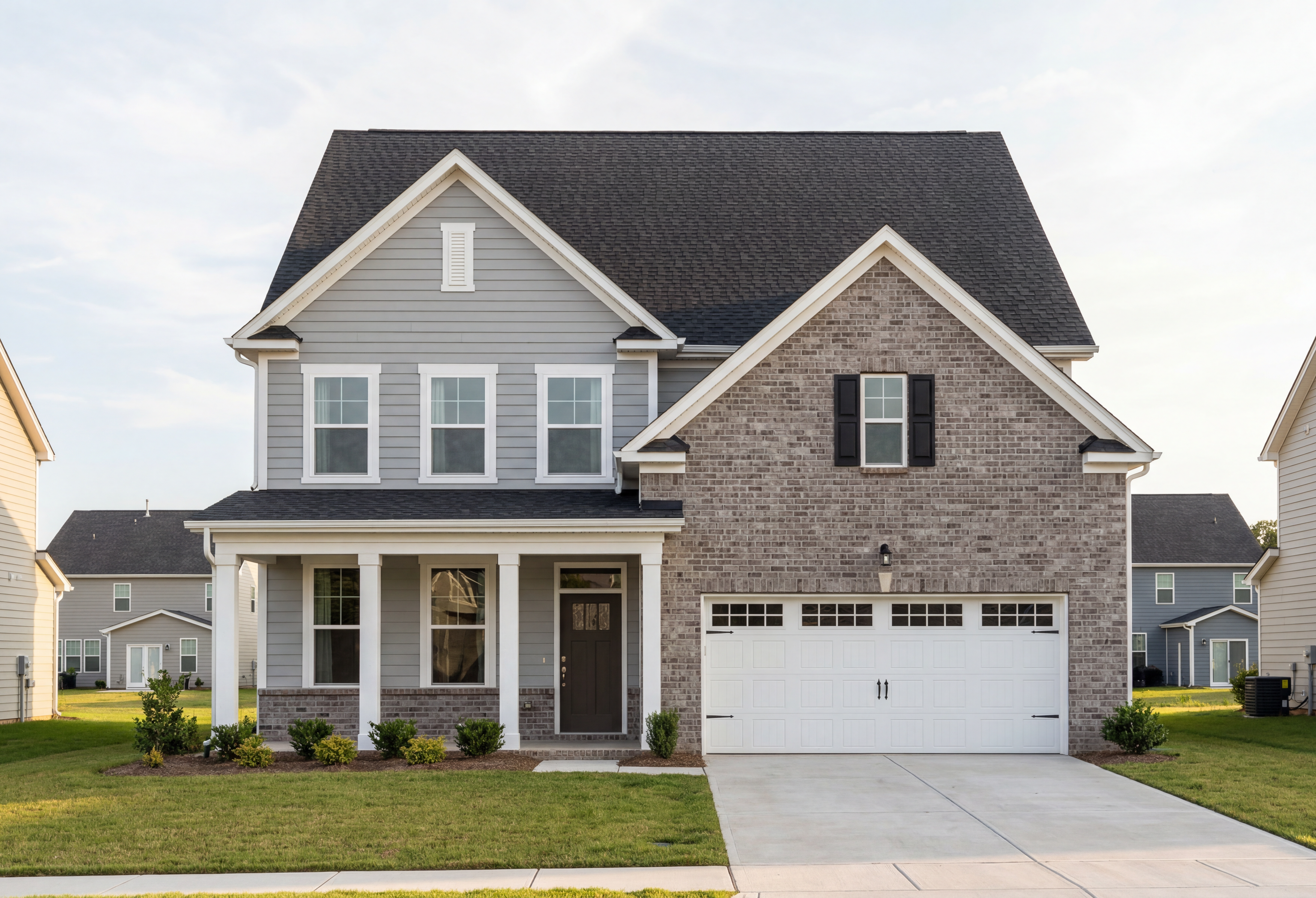 Two-story Hickory II home elevation featuring brick and vinyl siding, covered front porch, and two-car garage in Lillington NC