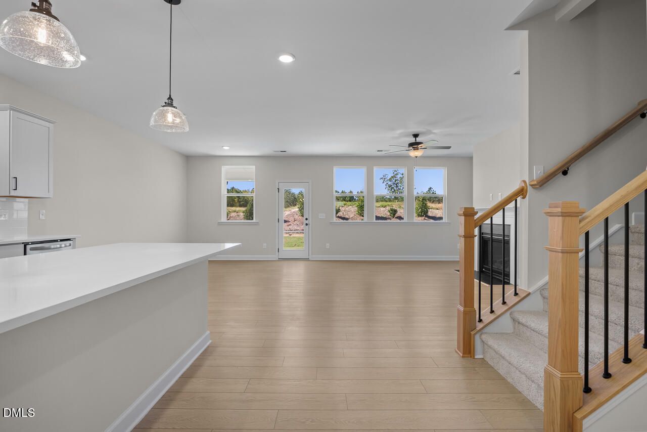 Open-concept living area with luxury vinyl plank flooring, staircase, fireplace, and natural light in Davidson Homes Ashport M plan